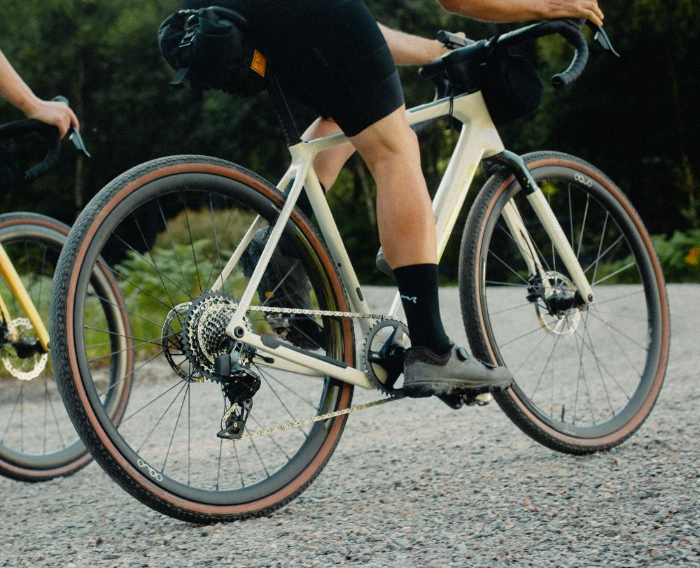 Zwei Radfahrer mit Orbea Terra Gravelbikes auf einem Schotterweg, ideal für Abenteuer und sportliches Fahren.