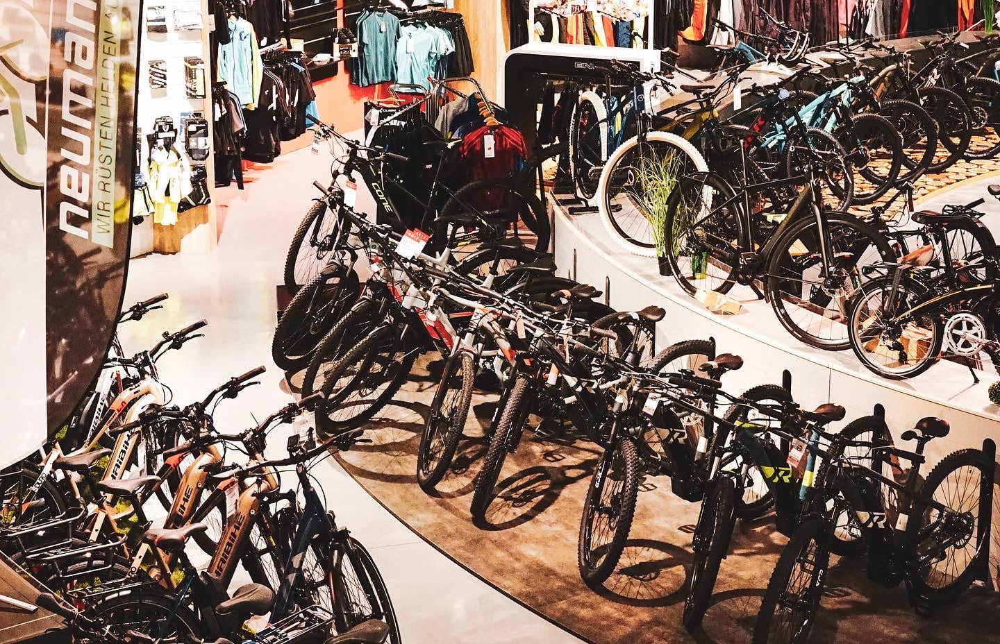 Fahrradgeschäft mit Neumann-Banner, verschiedene Fahrräder ausgestellt, inklusive Mountainbikes und Zubehör.