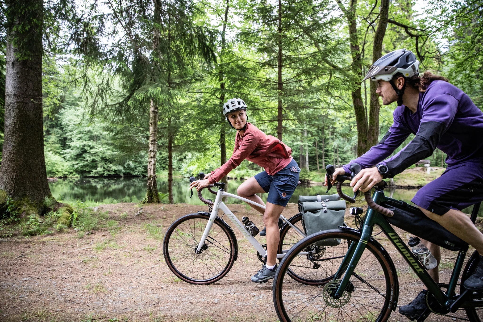 Zwei Personen auf Fahrrädern der Marke Diamant im Wald unterwegs, tragen sportliche Kleidung und Helme.