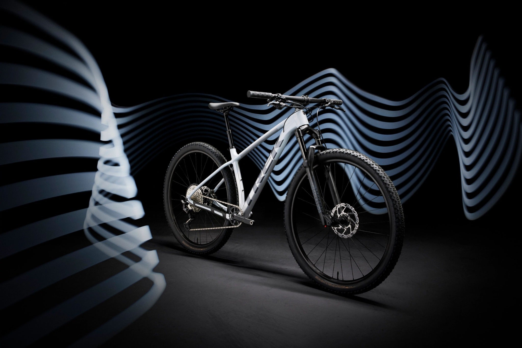 Mountainbike Trek Hardtail vor schwarzem Hintergrund mit wellenförmigem Design. Ideal für Outdoor-Radfahrer.