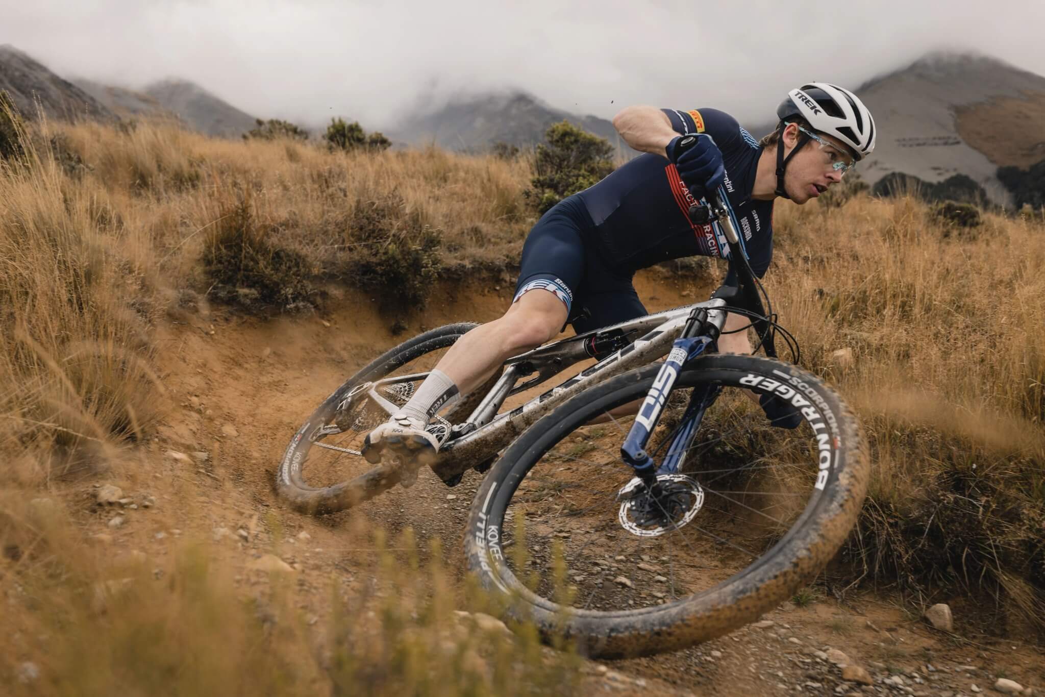 Mountainbiker fährt ein Trek-Fully durch eine kurvige, staubige Berglandschaft. Ideal für Offroad-Abenteuer.