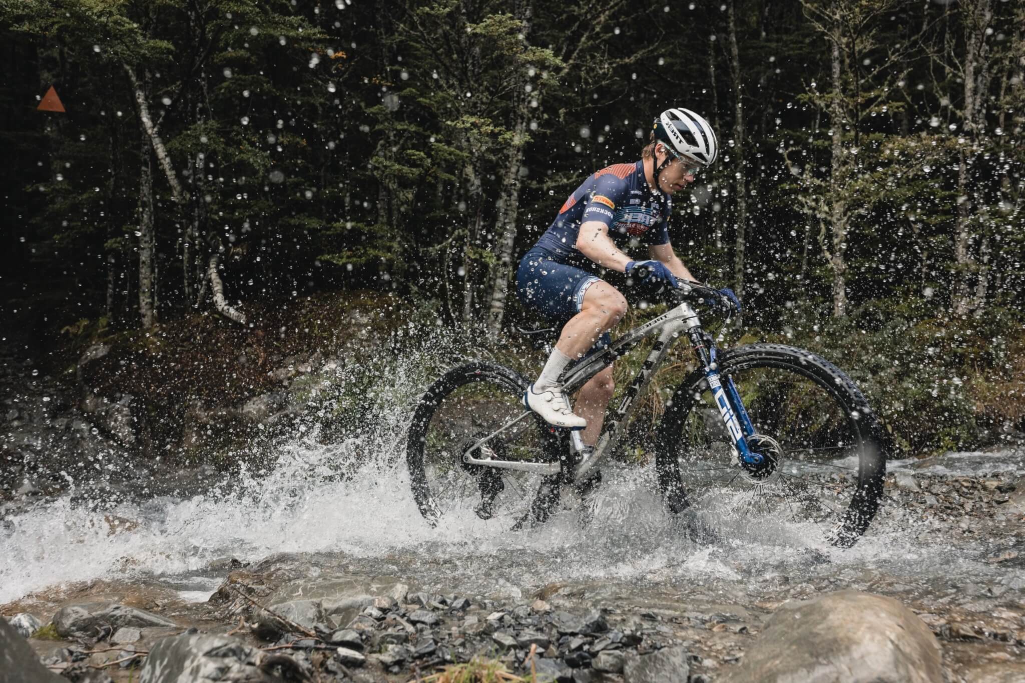 Radfahrer überquert Bach mit Trek Mountainbike im Wald, spritzendes Wasser.