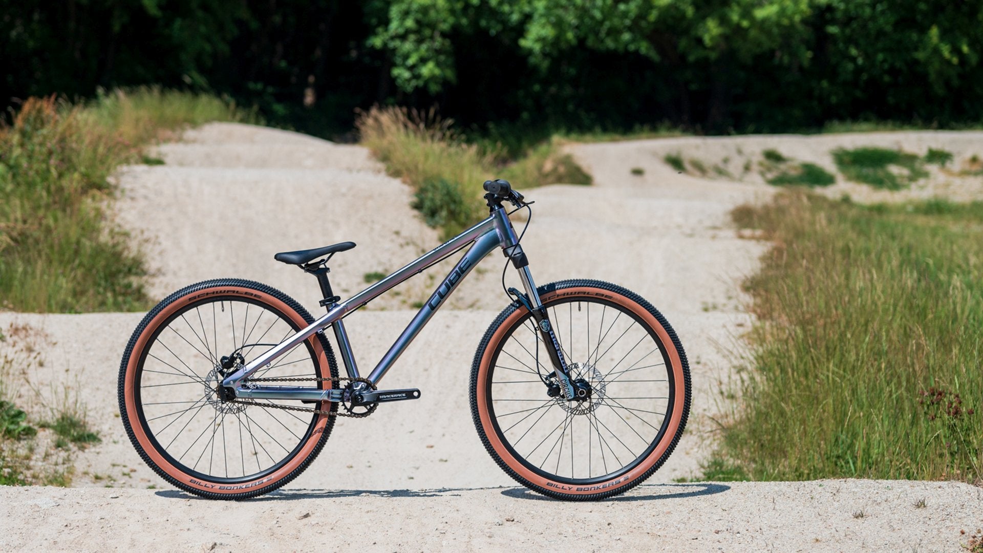 Cube Flying Circus Dirtbike im Gelände, ideal für BMX-Fans, silbernes Design mit braunen Reifen für Trick- und Springübungen.