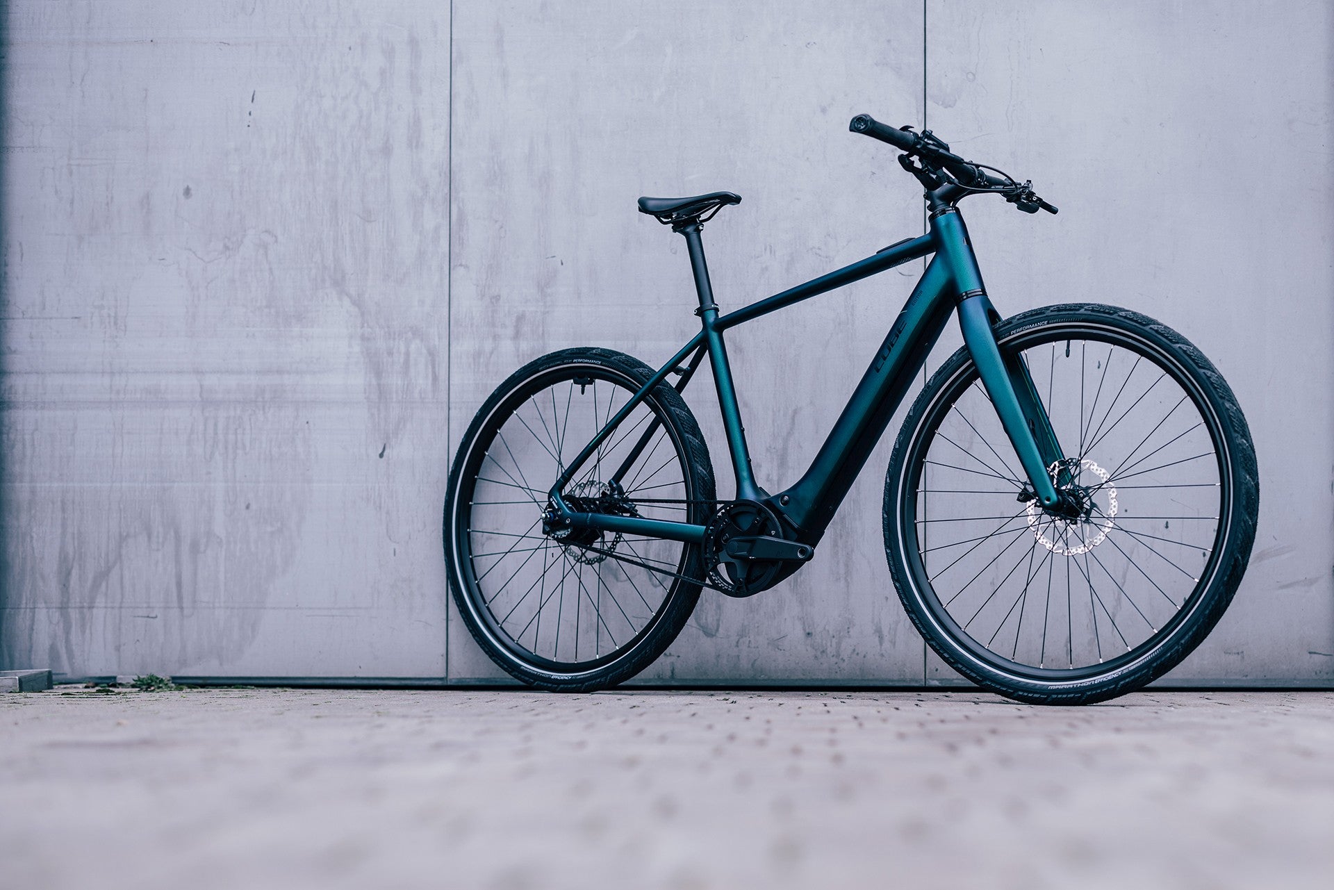 Cube Editor Hybrid E-Bike vor grauer Betonwand, für den urbanen Einsatz geeignet.