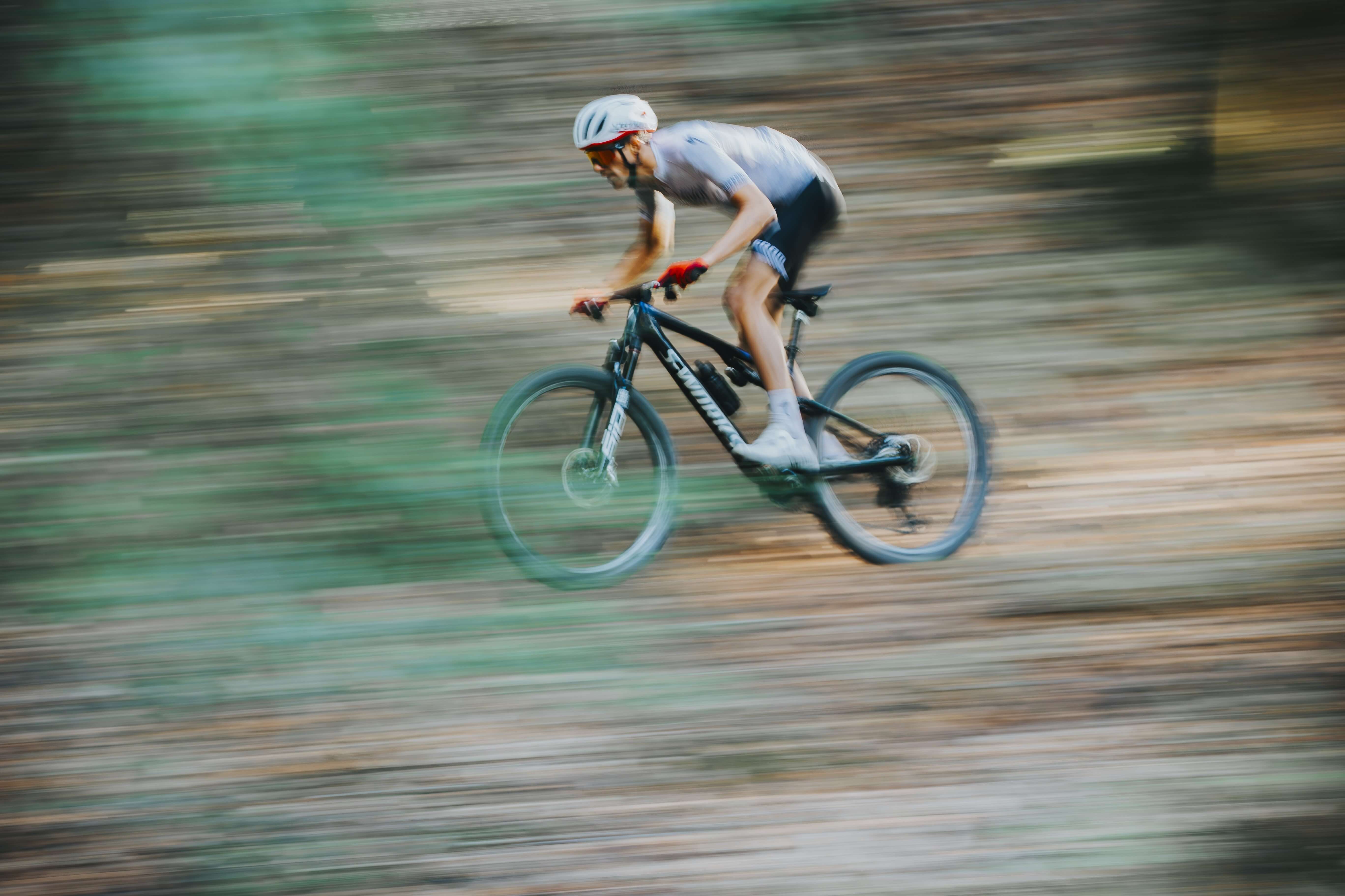 Rennradfahrer auf einem Specialized Epic Mountainbike im Wald, trägt Helm und Sportkleidung, Bewegungseffekt.