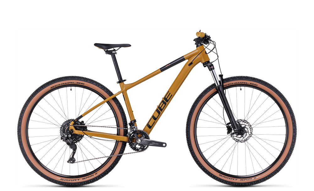 Goldenes Cube Mountainbike mit schwarzem Sattel, Scheibenbremsen und Schwalbe-Reifen. Ideal für Offroad-Abenteuer.