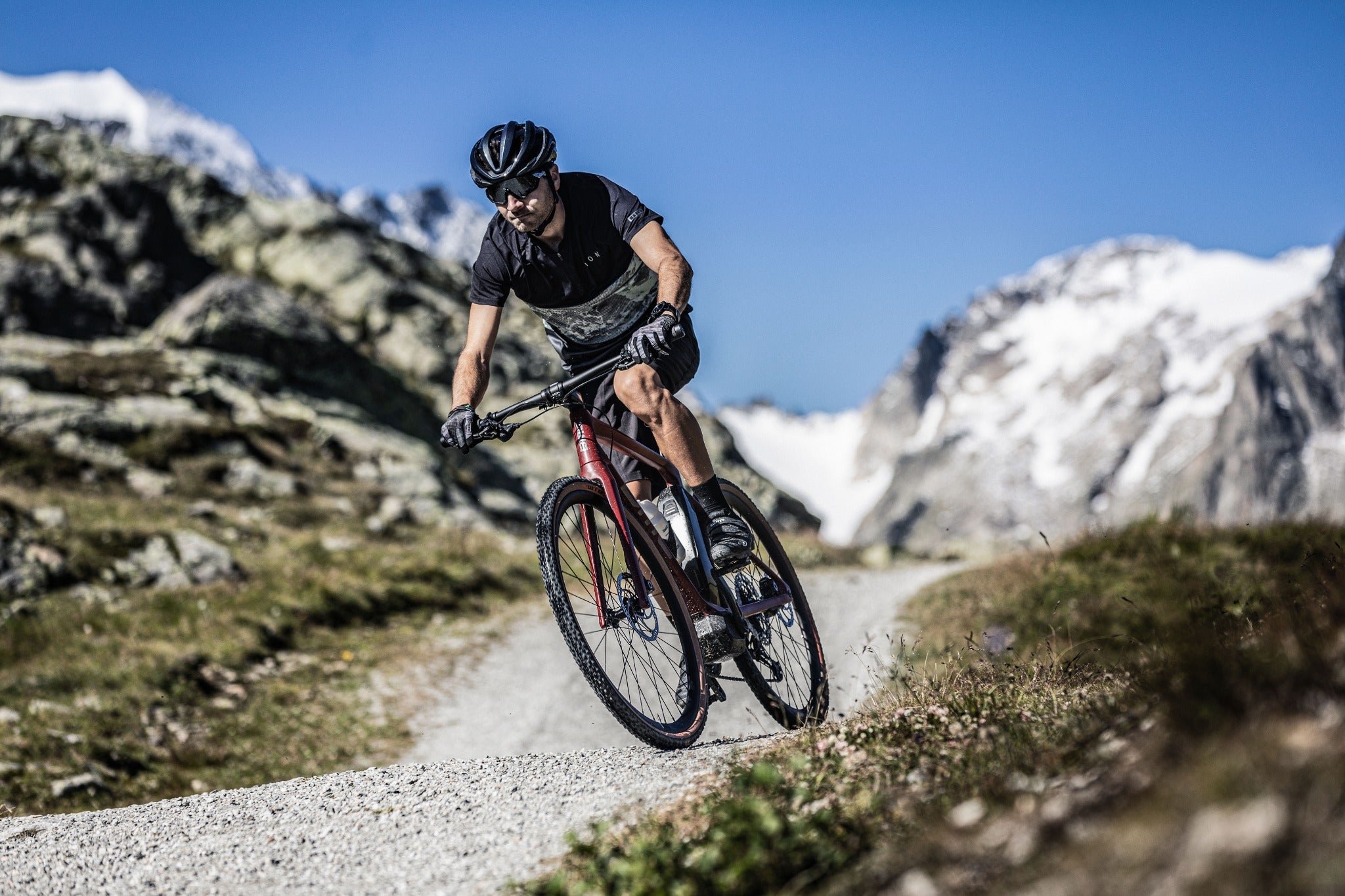 Radfahrer auf einem BMC E-Bike auf Bergweg, umgeben von alpiner Landschaft; Outdoor-Abenteuer.