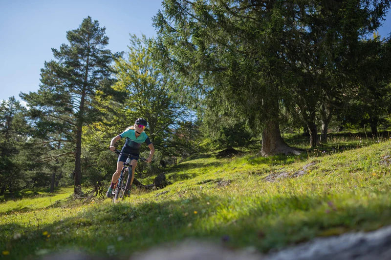 Mountainbiker auf einem Cube Hardtail in grüner Waldlandschaft. Ideal für Abenteuer im Gelände.