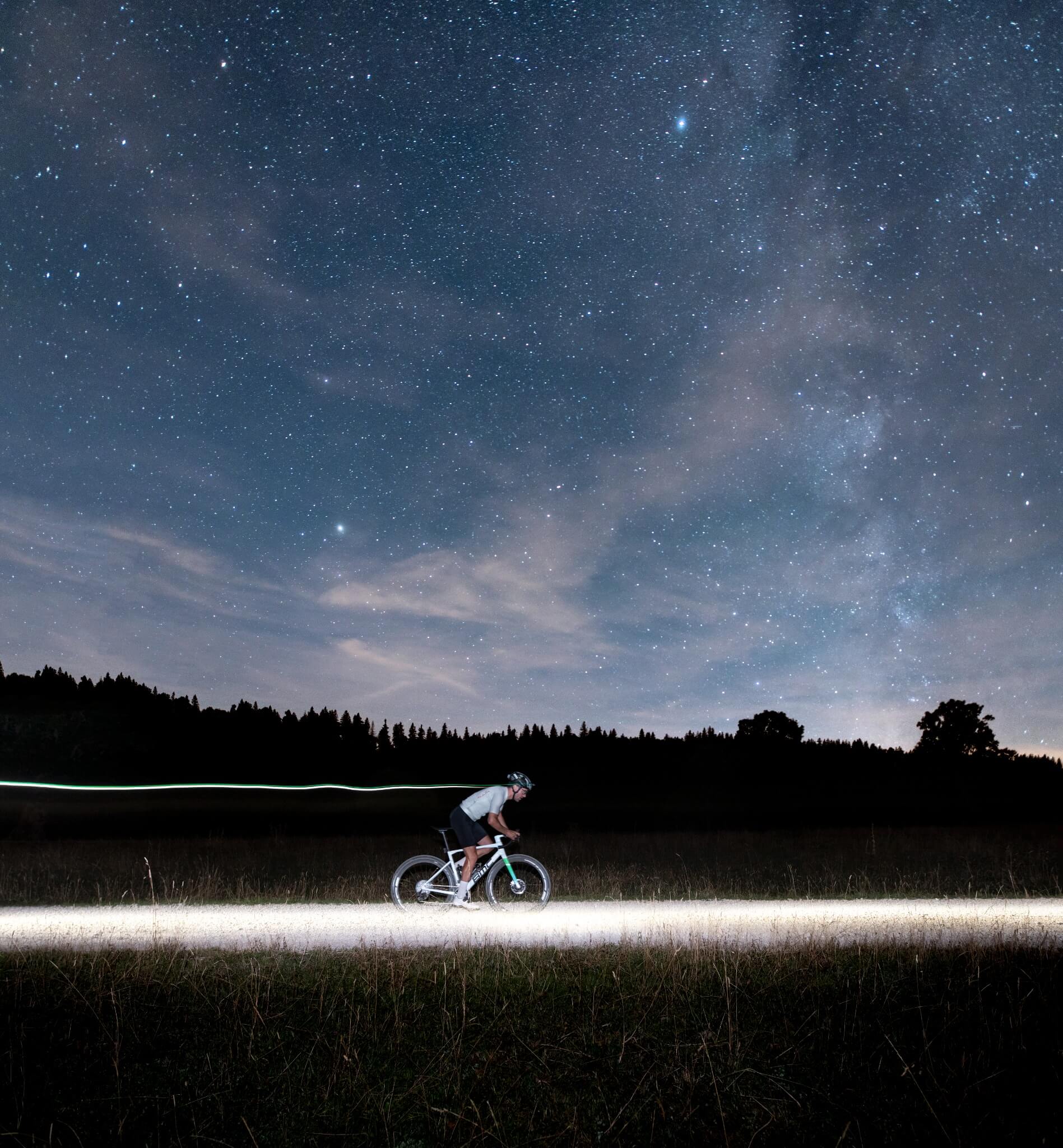 Radfahrer bei Nacht auf einem BMC Kaius unter sternenklarem Himmel, eignet sich für Radsportfans und Outdoor-Abenteuer.