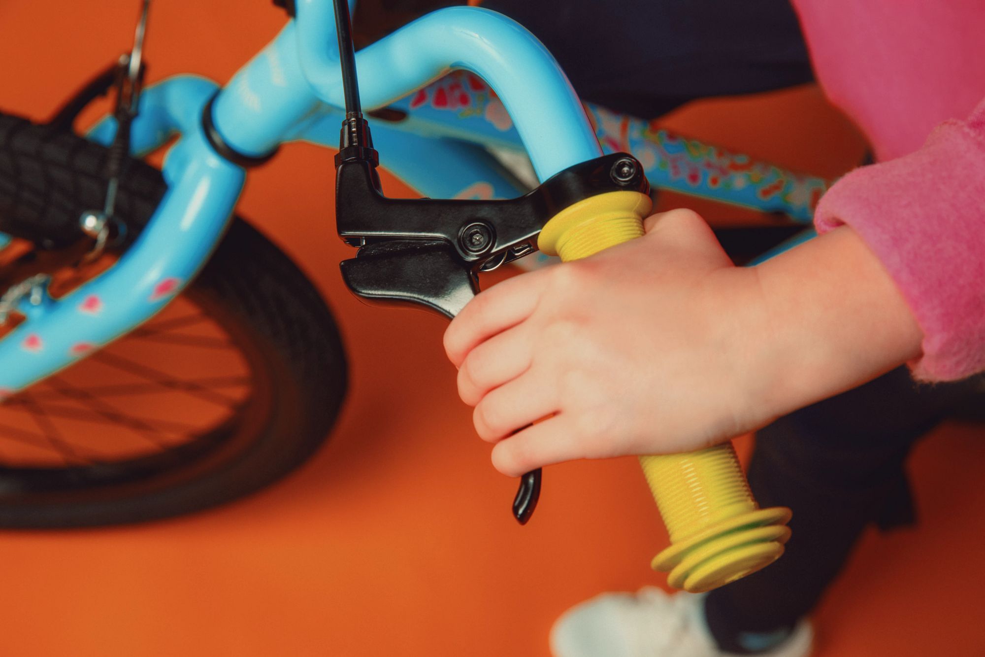 Nahaufnahme eines Kinderfahrrads von Cannondale, blau mit gelbem Griff, Hand eines Kindes am Bremshebel.