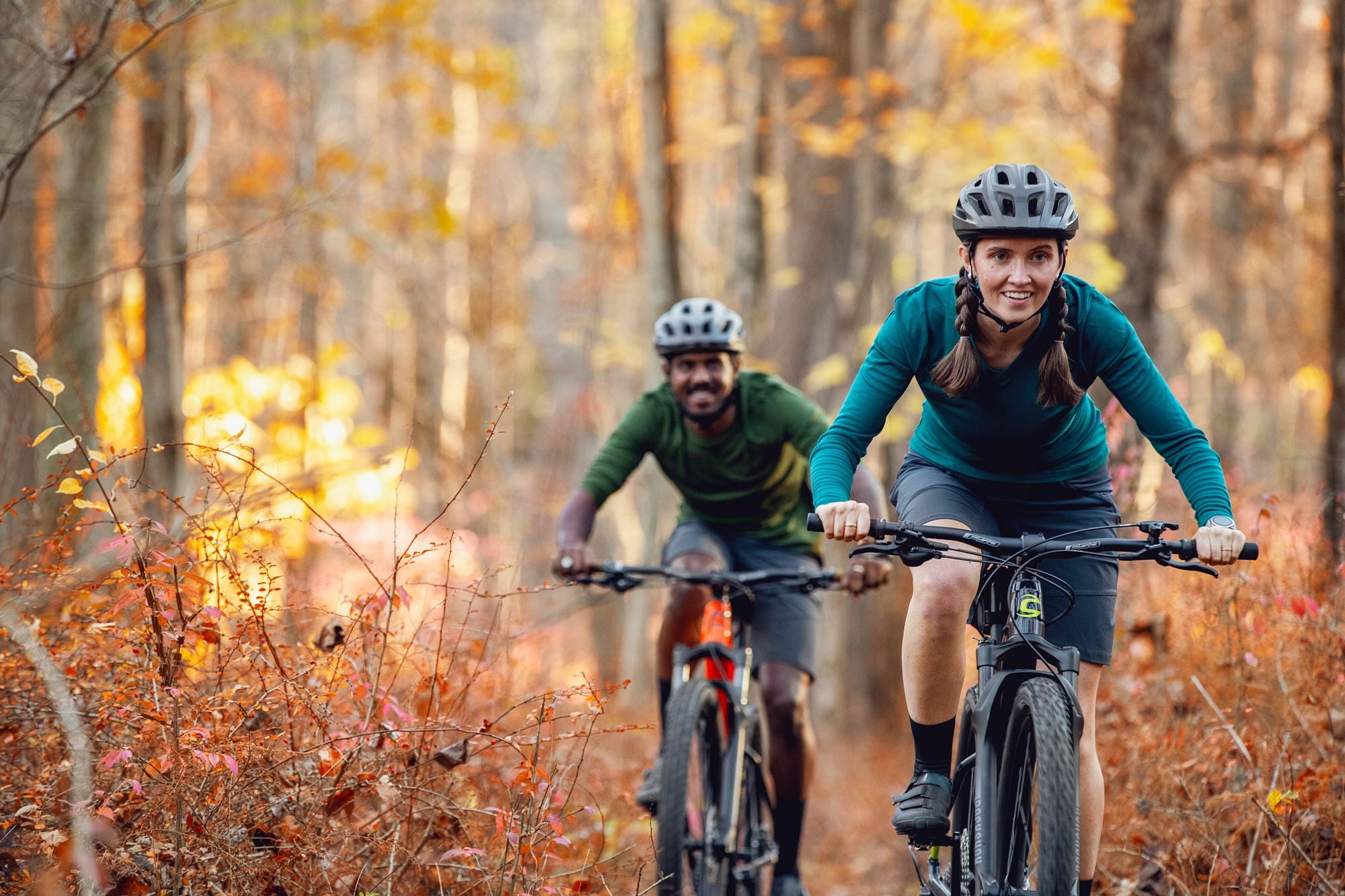 Zwei Personen fahren Cannondale Hardtail-Mountainbikes durch einen herbstlichen Wald.