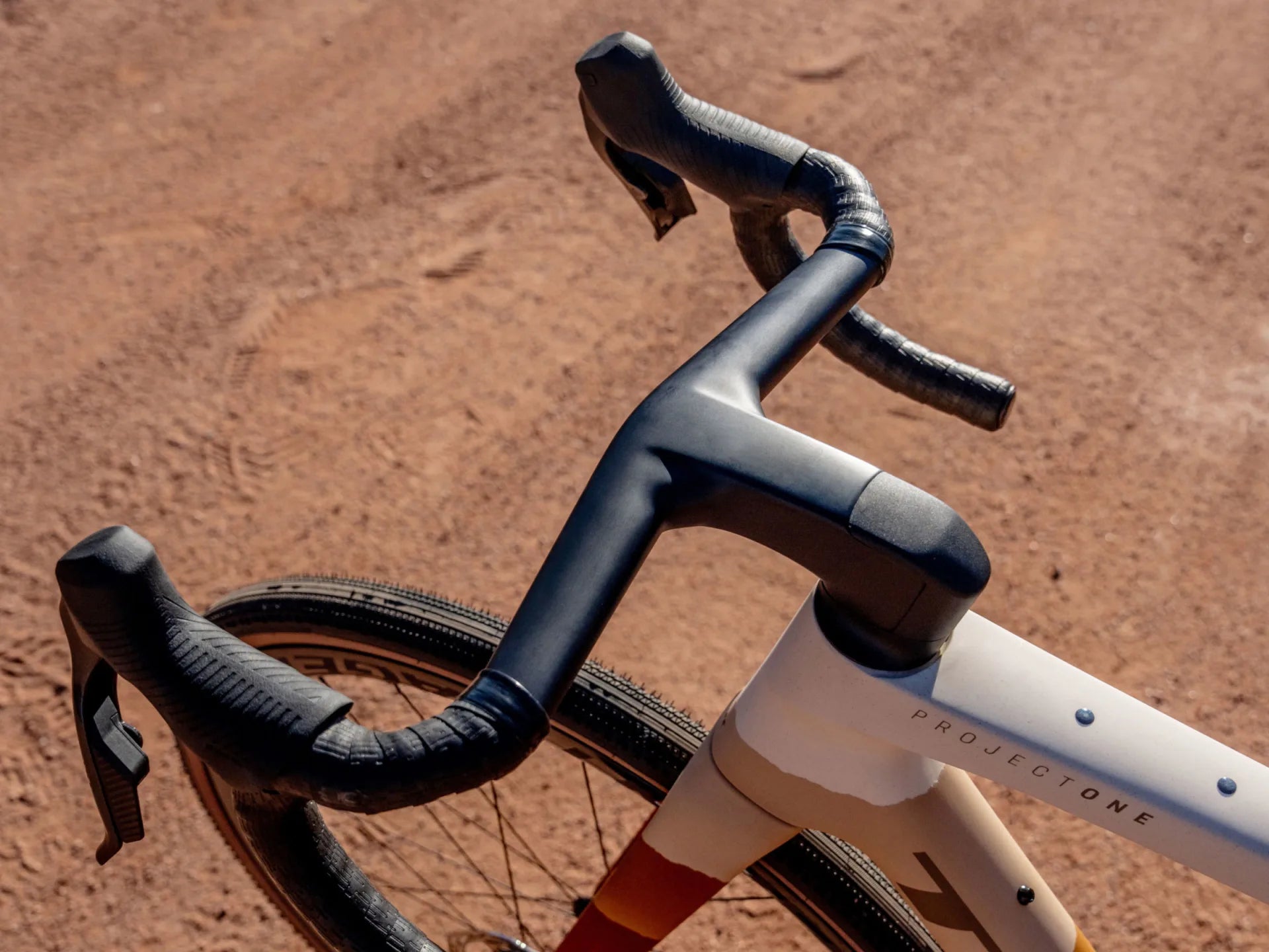 Rennradlenker mit Aerolenkervorbau und Schriftzug "Project One" auf sandigem Untergrund, geeignet für ambitionierte Radfahrer.