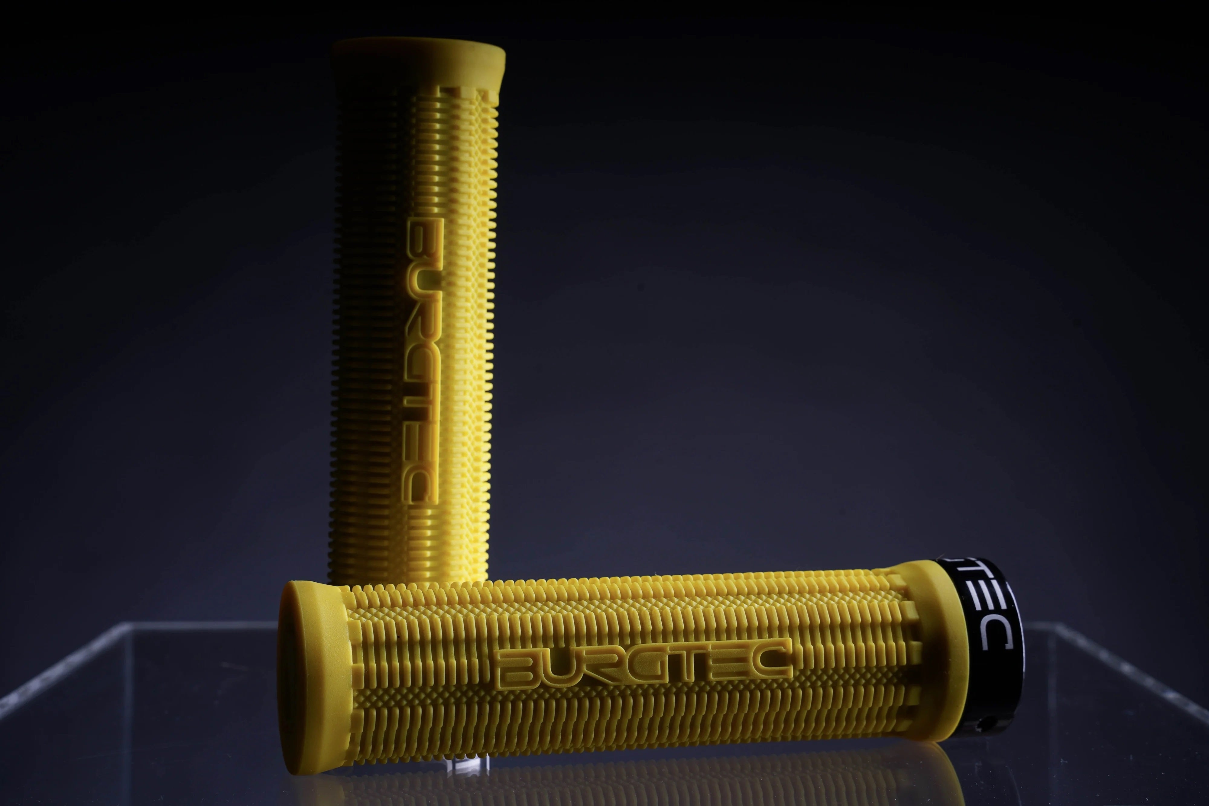Gelbe Fahrradgriffe von Burgtec mit rutschfestem Design, ideal für Mountainbikes, auf dunklem Hintergrund.