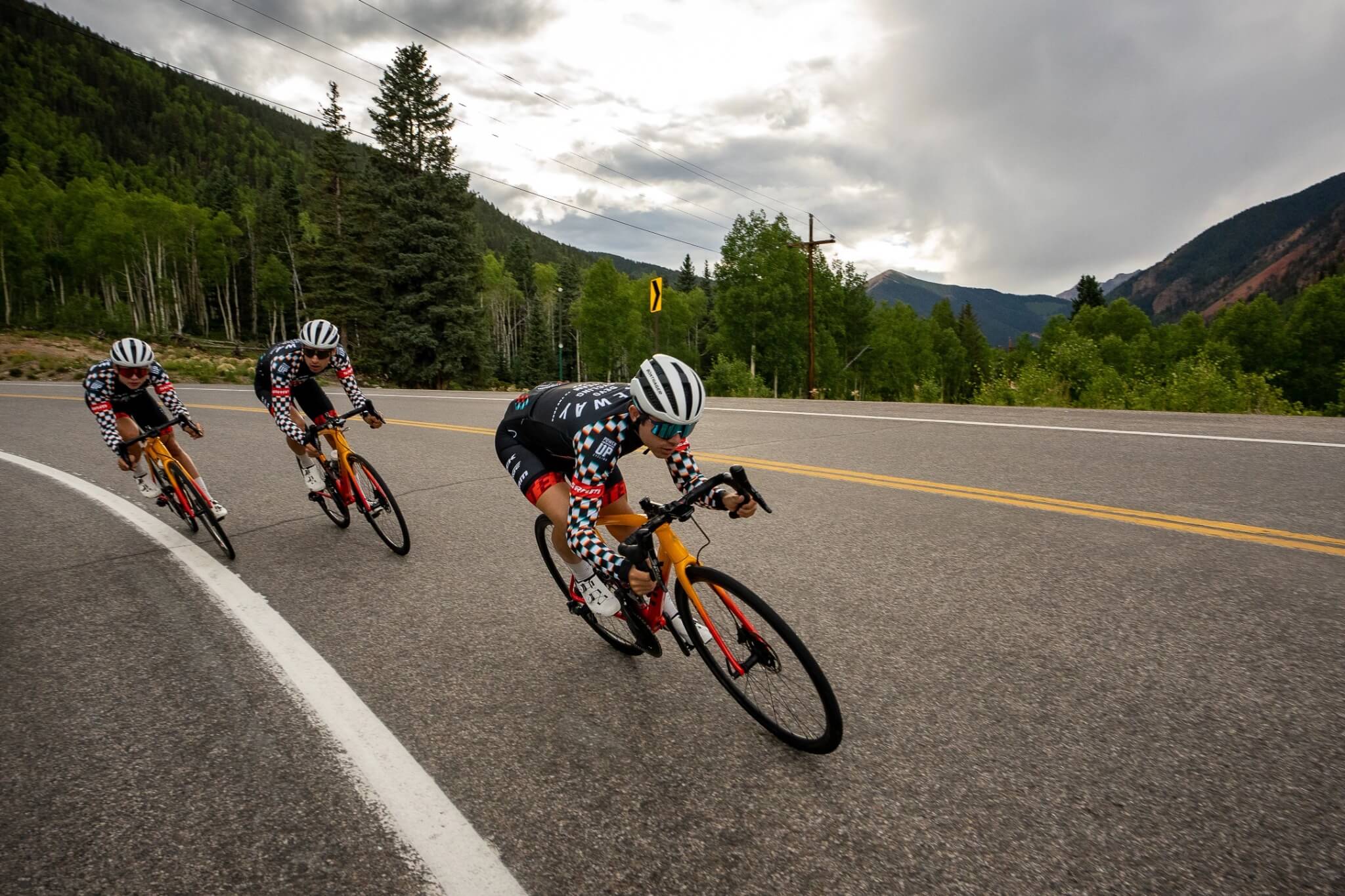 Drei Radrennfahrer auf einer kurvigen Bergstraße; Trek Rennräder, geeignet für sportliche Wettkämpfe und ambitionierte Fahrer.