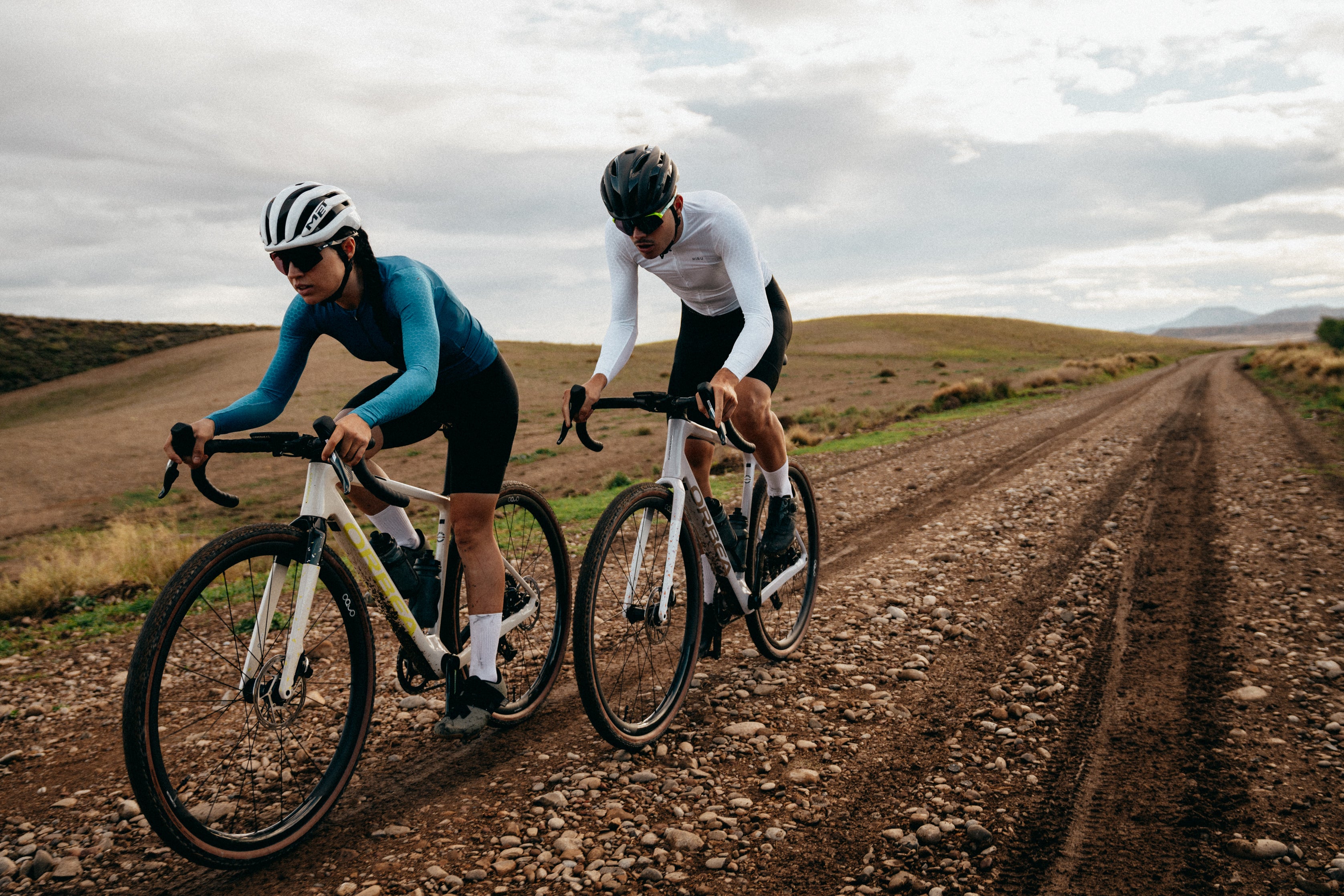 Zwei Radfahrer auf einem Schotterweg mit Orbea-Fahrrädern, geeignet für Outdoor-Abenteuer und Fitness.