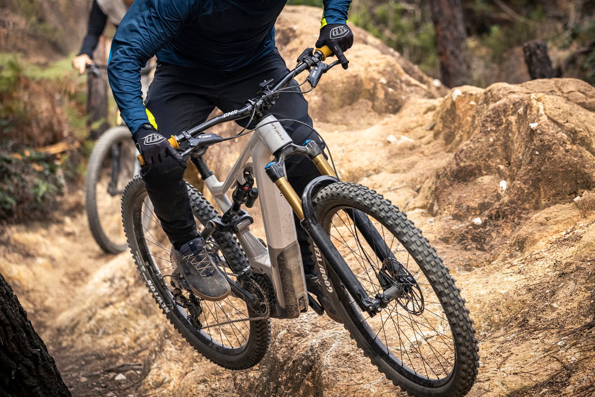 Mountainbiker fährt Focus E-Bike über felsigen Trail im Wald. Ideal für Offroad-Abenteuer.