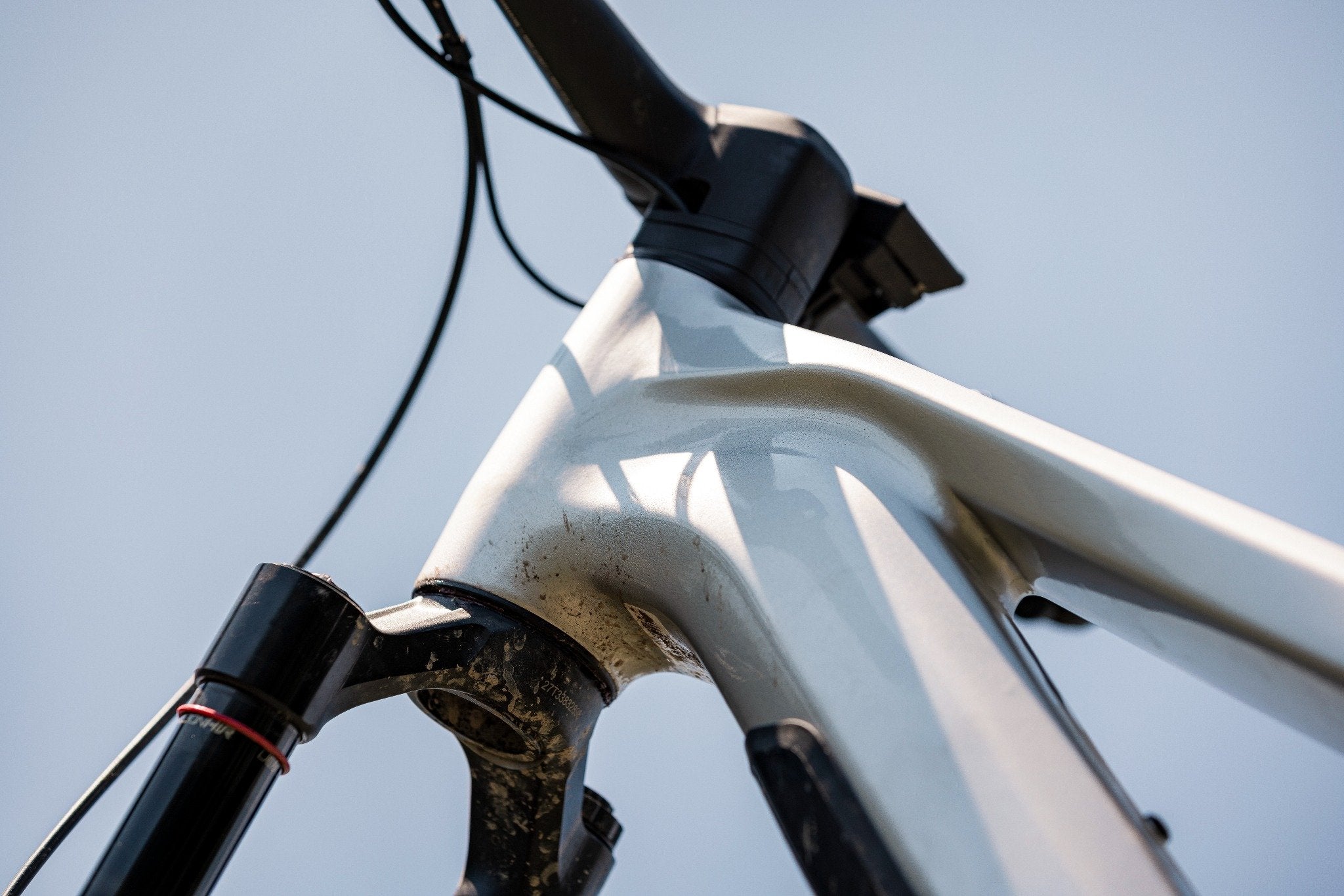 Nahaufnahme eines weißen Mountainbike-Rahmens mit schwarzer Federgabel, geeignet für Offroad-Fahrten.