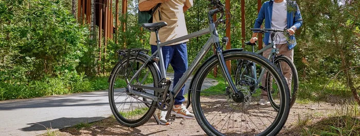 Zwei Personen stehen neben modernen Gazelle Bikes auf einem Waldweg. Ideal für Outdoor-Enthusiasten und Stadtpendler.