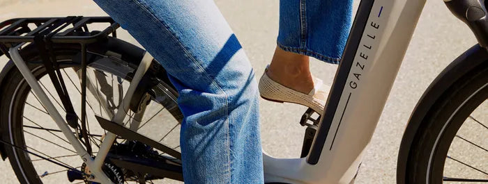 Person auf Gazelle Bike, trägt blaue Jeans, fährt auf Straße. Ideal für städtische Mobilität und umweltfreundliches Pendeln.