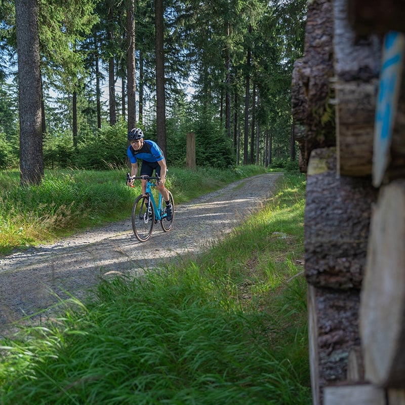 Ein Radfahrer auf einem Schotterweg im Wald auf einem Cube Cross Race Fahrrad.