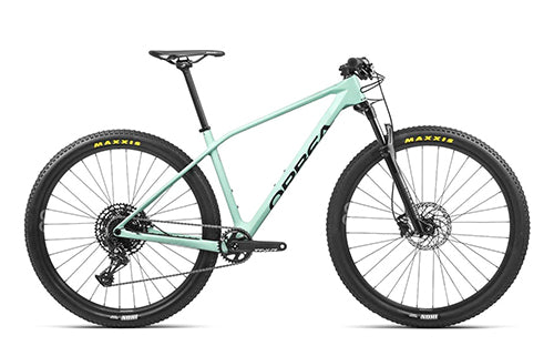 Mintgrünes Hardtail-Mountainbike von Orbea, Modell für Offroad-Fahrten, 29-Zoll-Räder mit Maxxis-Reifen.