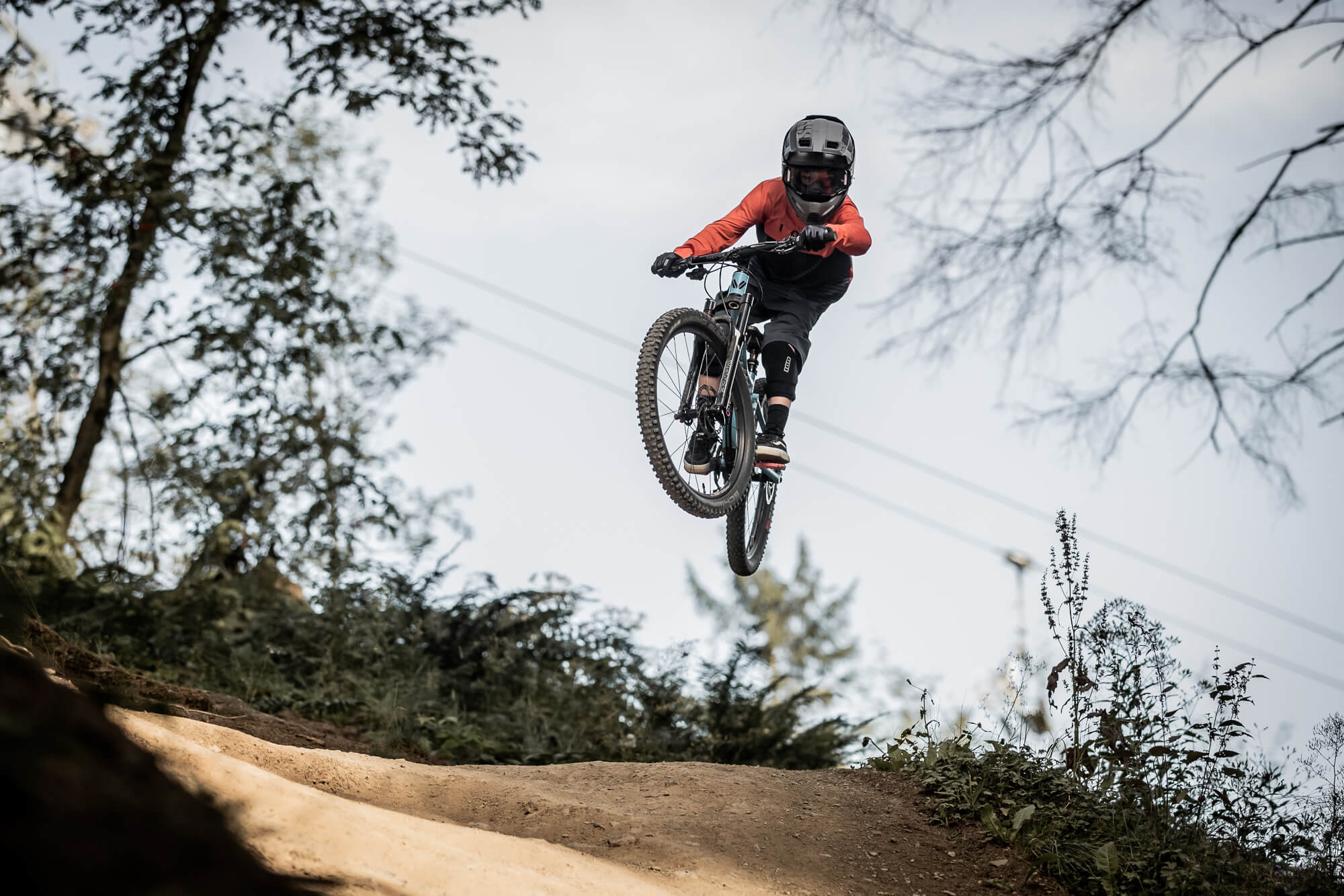 Kind auf einem Mountainbike in der Luft, trägt Helm und Schutzkleidung, gemacht für Offroad-Abenteuer und Action.