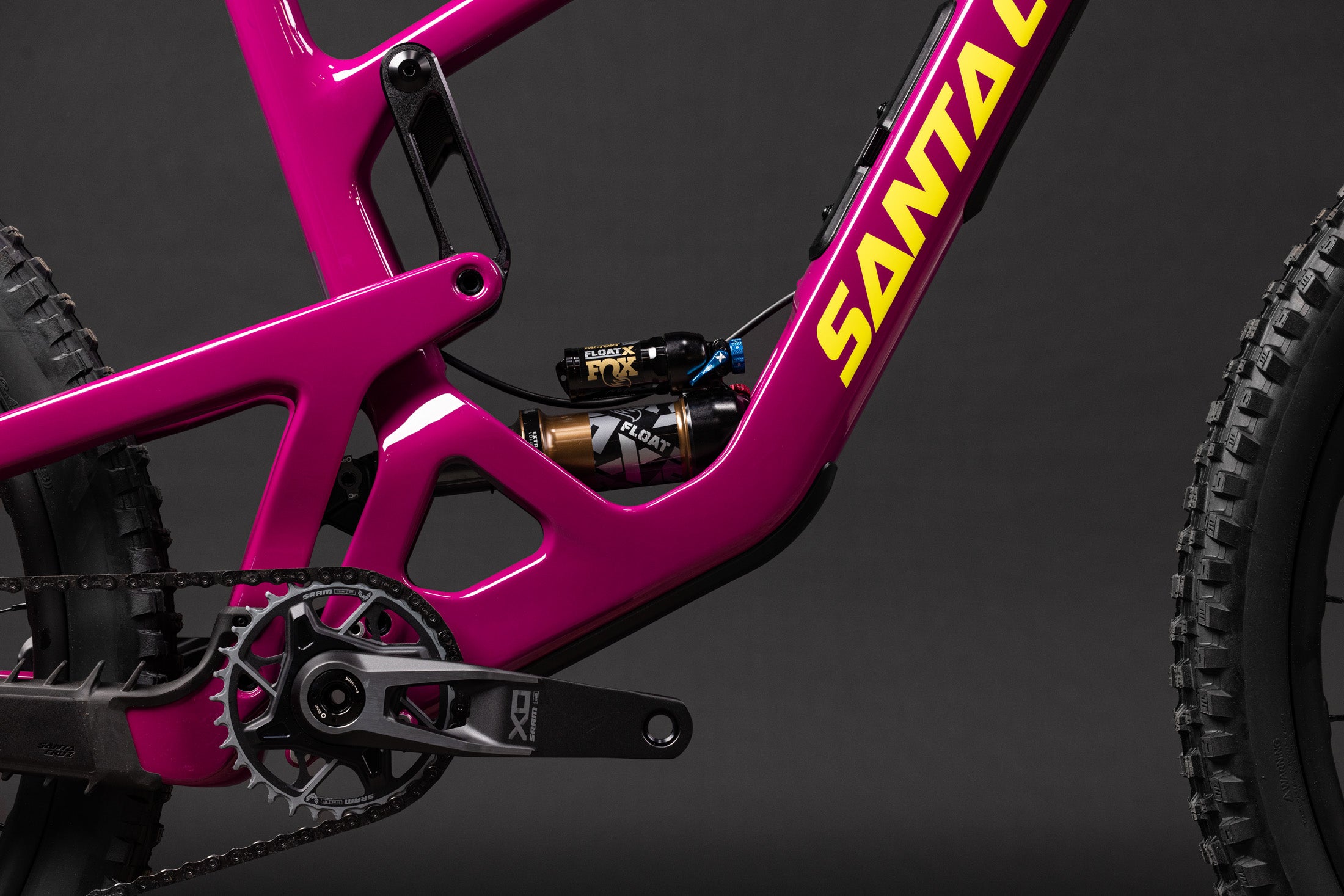 Rosafarbener Santa Cruz Bronson Fahrradrahmen mit FOX-Float-Dämpfer und SRAM XO Kurbelgarnitur, Nahaufnahme.