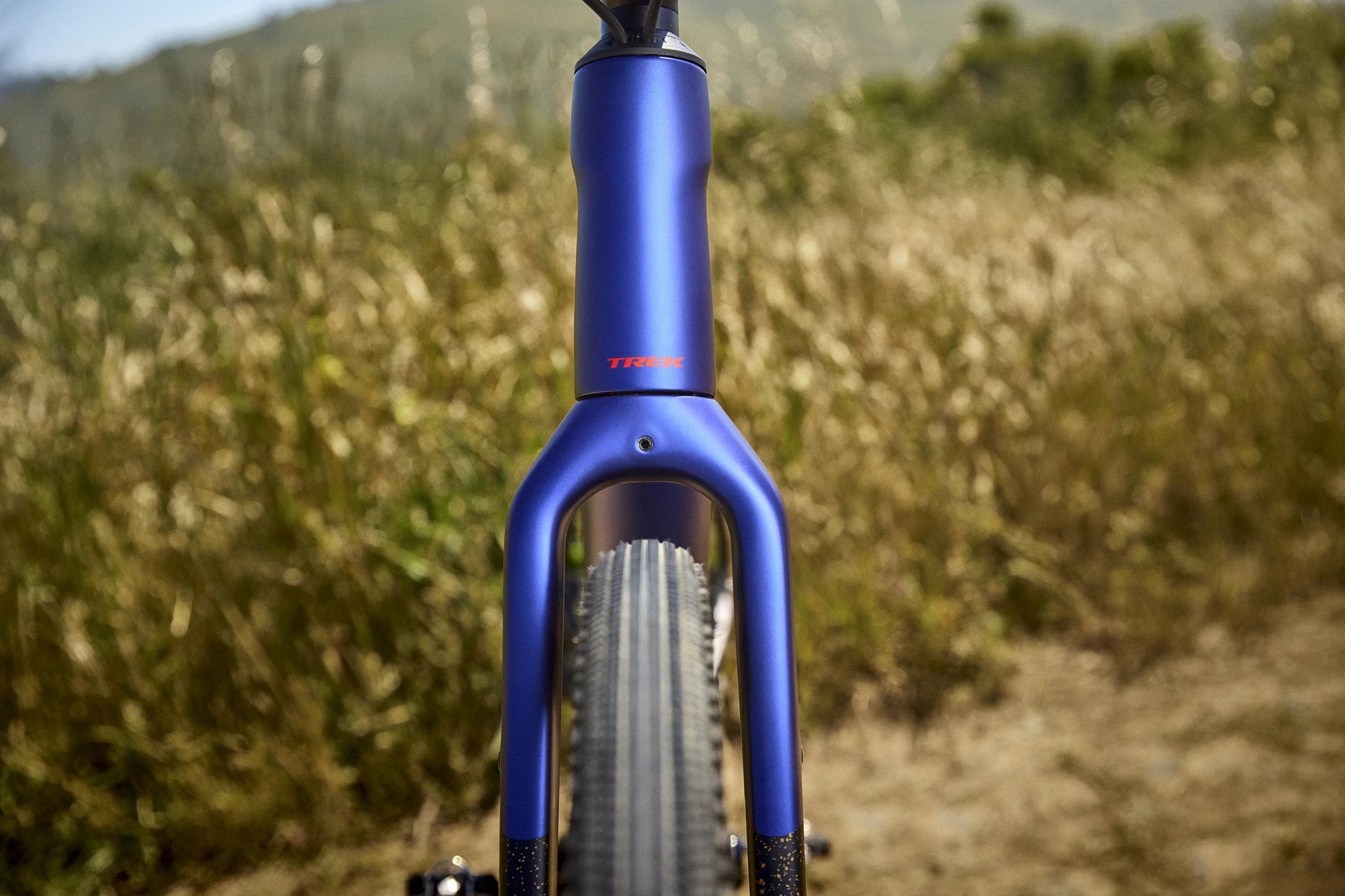 Blaues Trek Gravelbike im Gelände, Vorderansicht der Gabel und Reifen, geeignet für Offroad-Abenteuer.