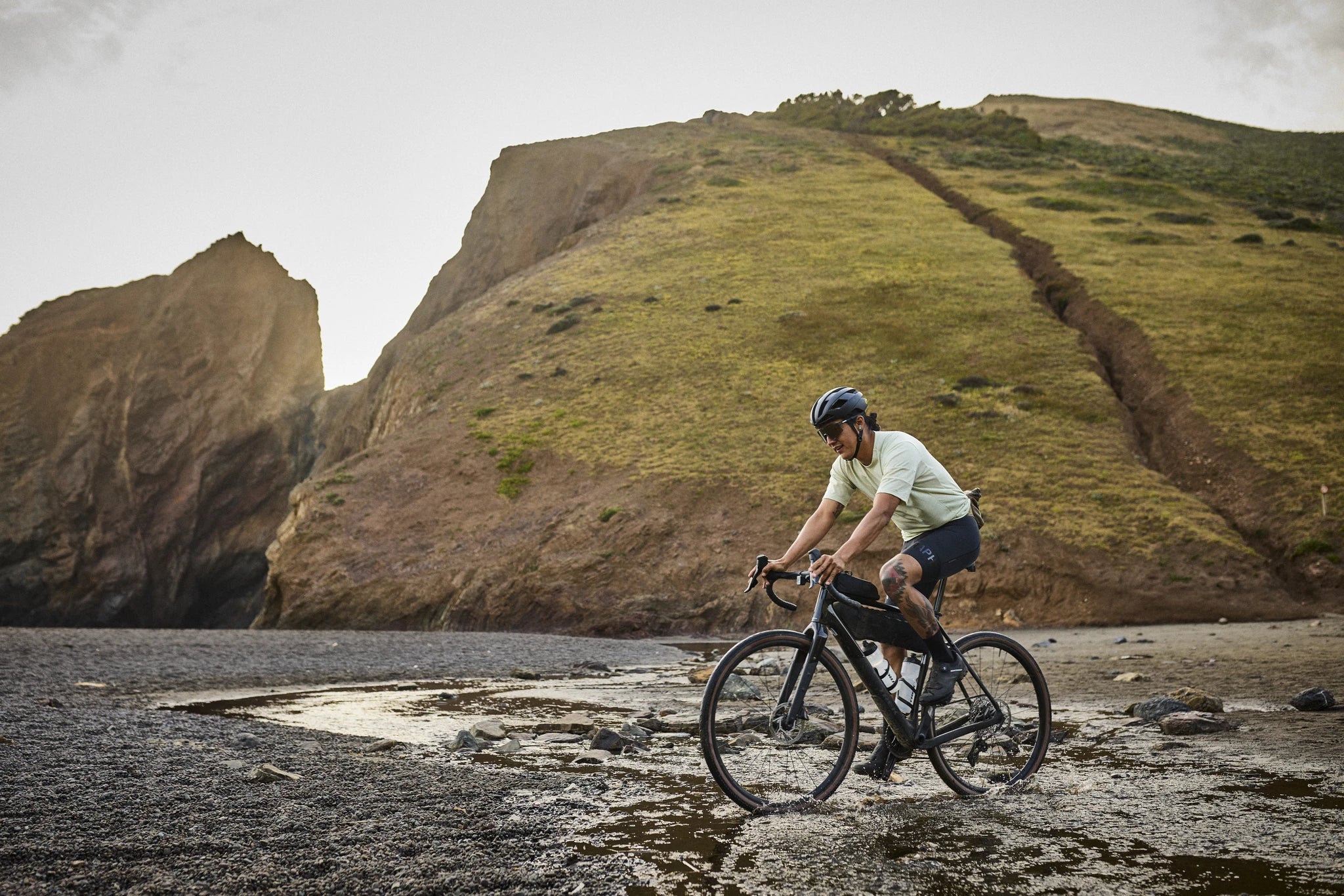 Person fährt Trek Gravelbike in hügeliger Landschaft auf steinigem Untergrund. Ideal für Outdoor-Abenteuer.