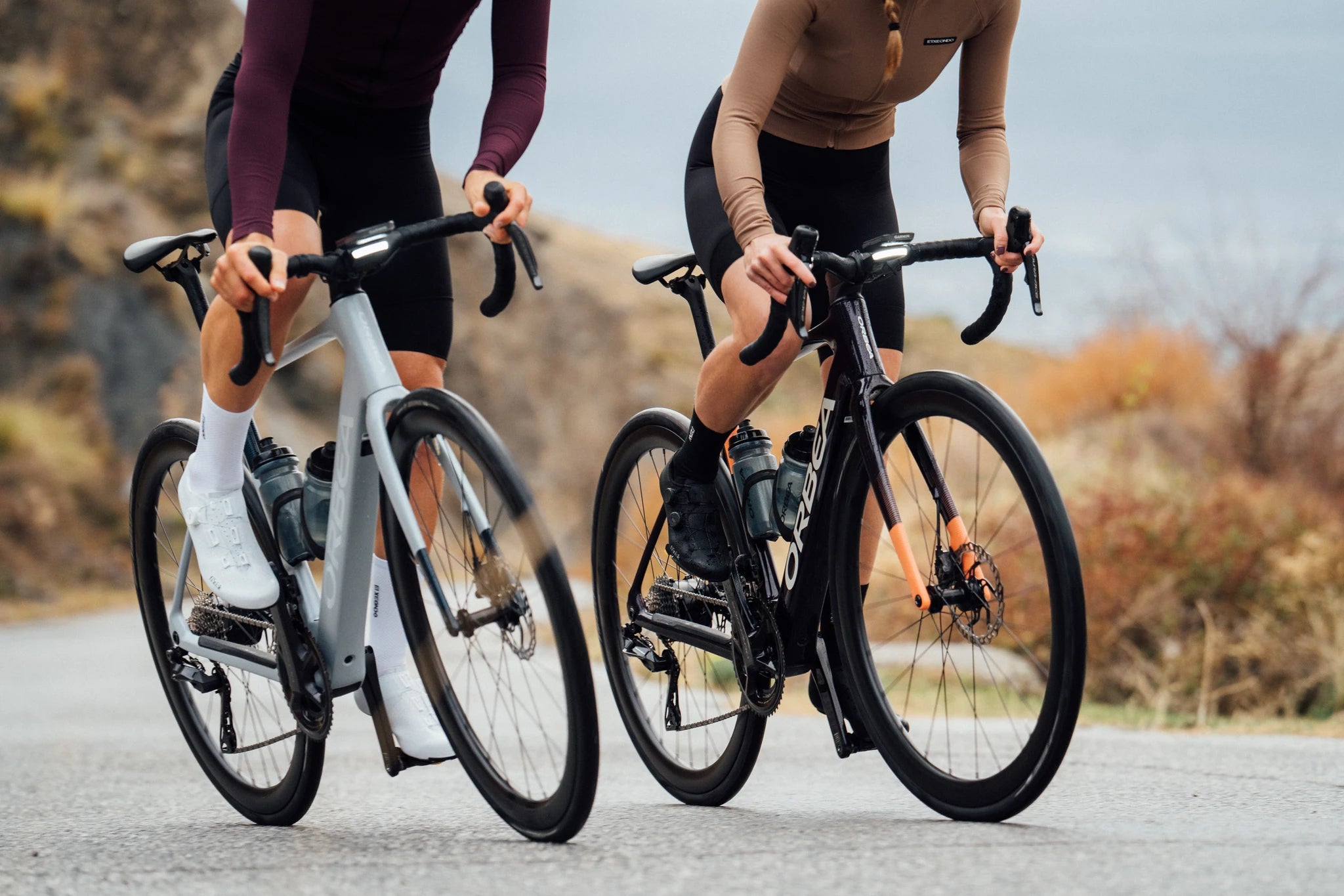 Zwei Personen fahren Orbea Gain Rennräder auf einer Straße. Perfekt für Fitness-Enthusiasten und Radfahr-Begeisterte.