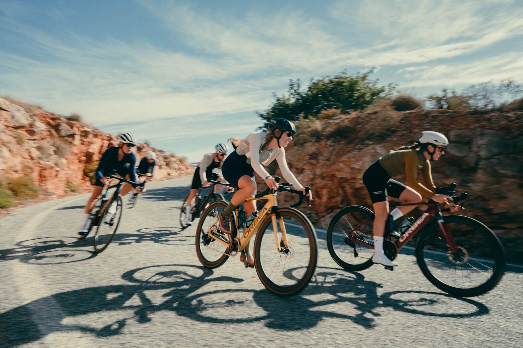 Gruppe von Radfahrern auf der Straße, auf Orbea-Rennrädern, fährt durch eine felsige Landschaft.