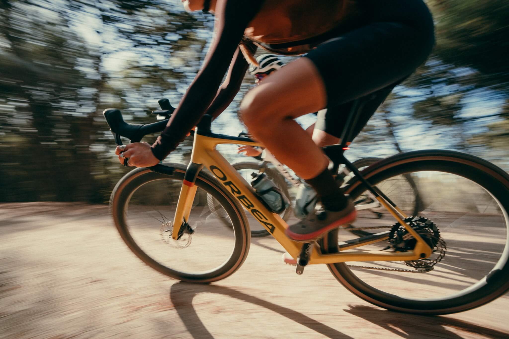 Person fährt schnelles Orbea-Rennrad durch eine bewaldete Gegend, geeignet für sportliche Radfahrer.