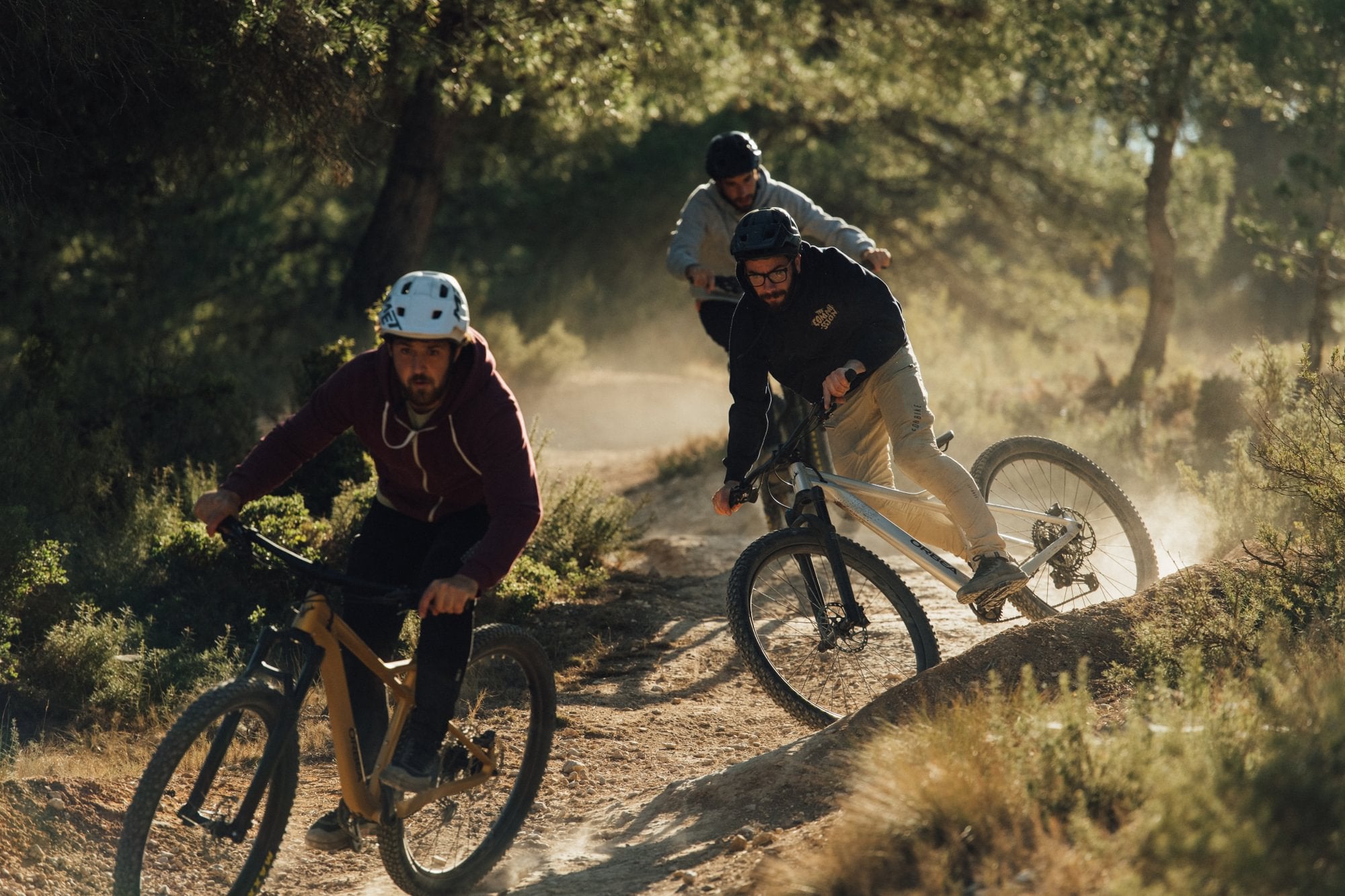 Drei Mountainbiker fahren auf einem Waldweg bergab; geeignet für sportliche Outdoor-Abenteuer.