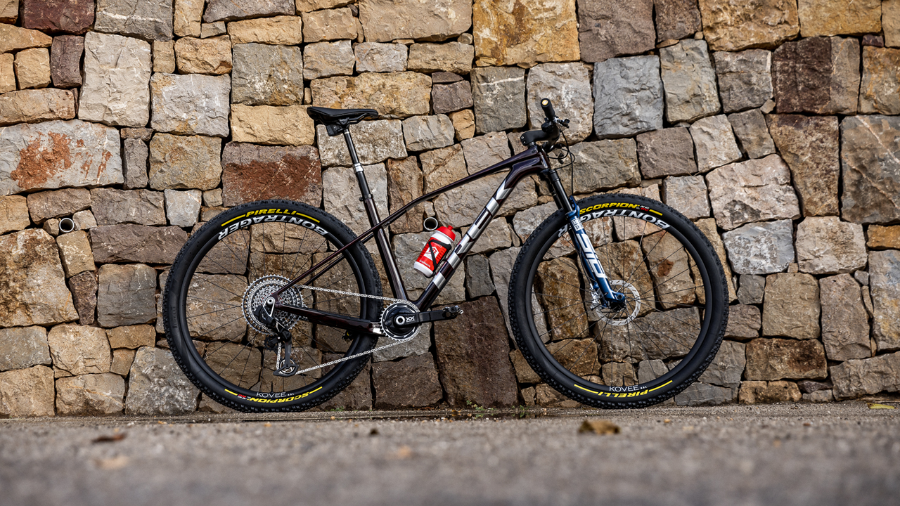 Mountainbike Trek Procaliber vor Steinmauer, geeignet für Offroad-Fahrten. Pirelli-Reifen und Flaschenhalter sichtbar.