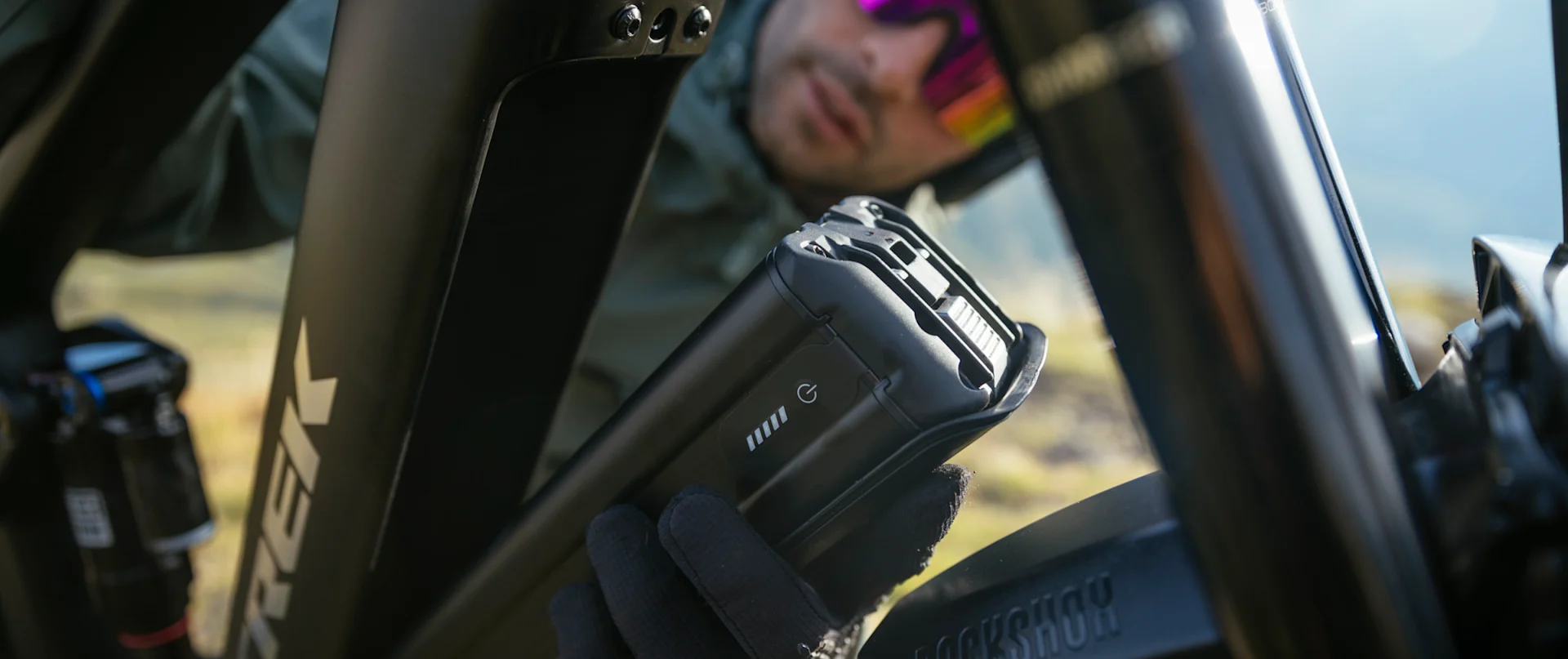 Mann setzt Akku in ein Trek E-Bike ein, Nahaufnahme des Rahmens mit "Trek"-Logo.