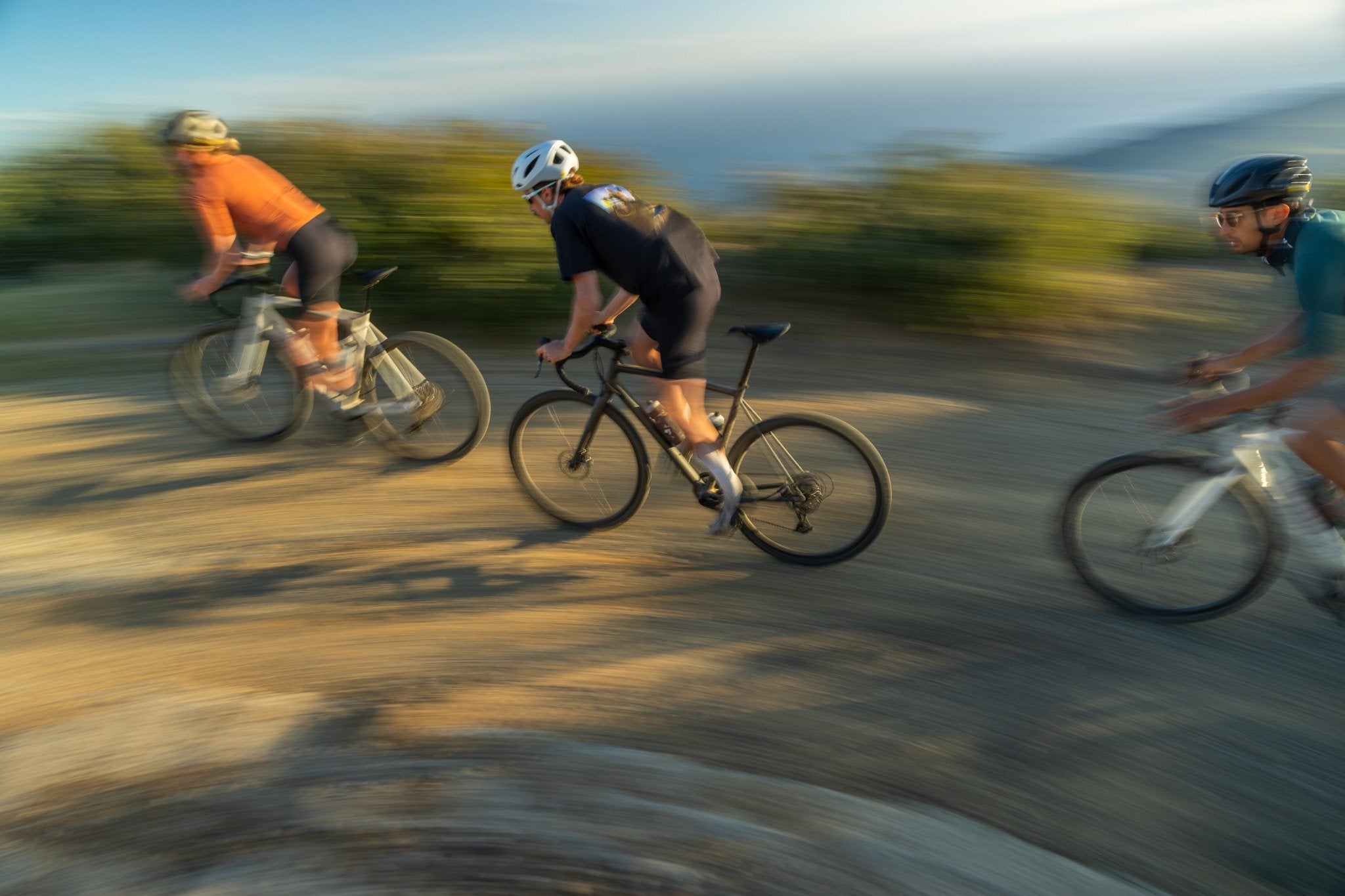 Drei Radfahrer auf einem Schotterweg, Schwerpunkt auf Geschwindigkeit und Abenteuer. Specialized Crux im Einsatz.