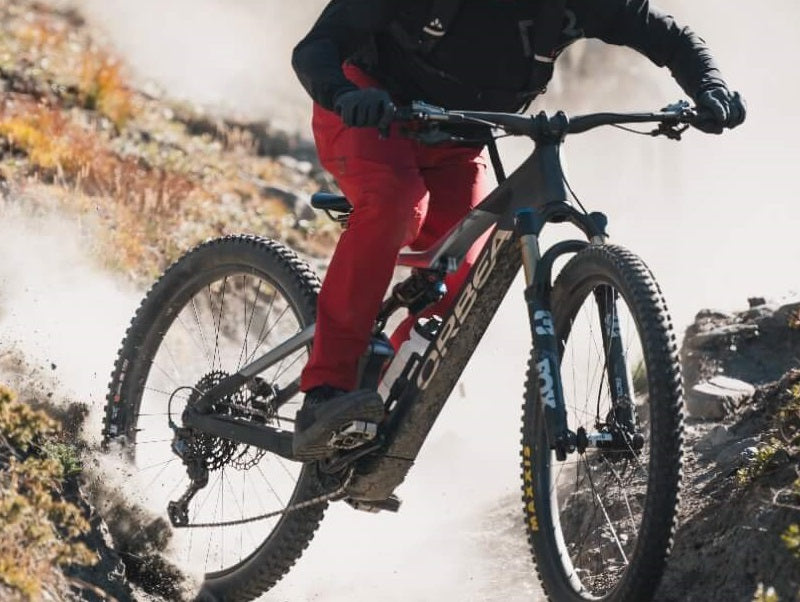 Biker fährt ein Orbea Mountainbike auf staubigem Pfad bergab.