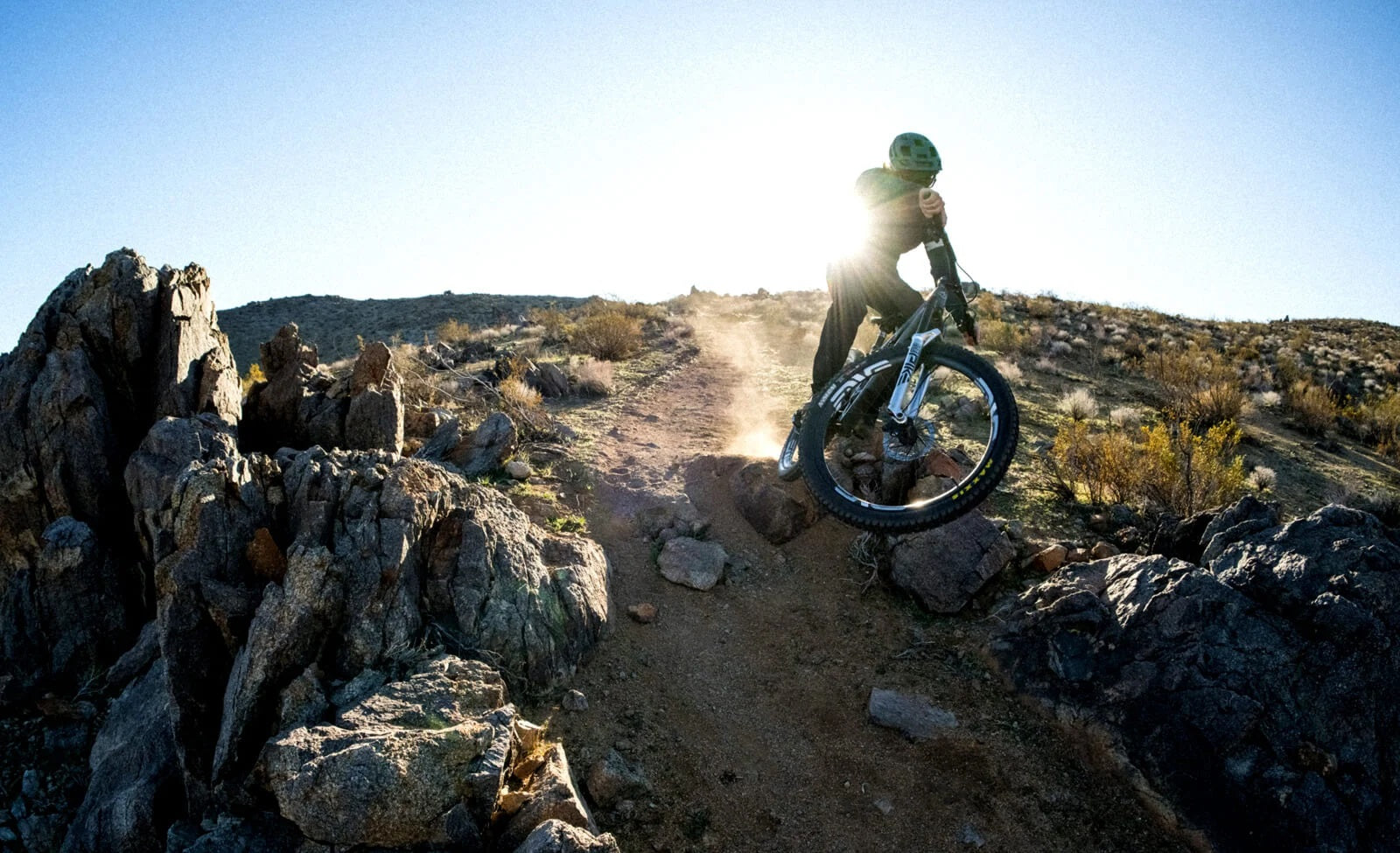 Mountainbiker auf steinigem Trail bei Sonnenuntergang, ausgestattet mit RockShox-Federung, ideal für Offroad-Abenteuer.