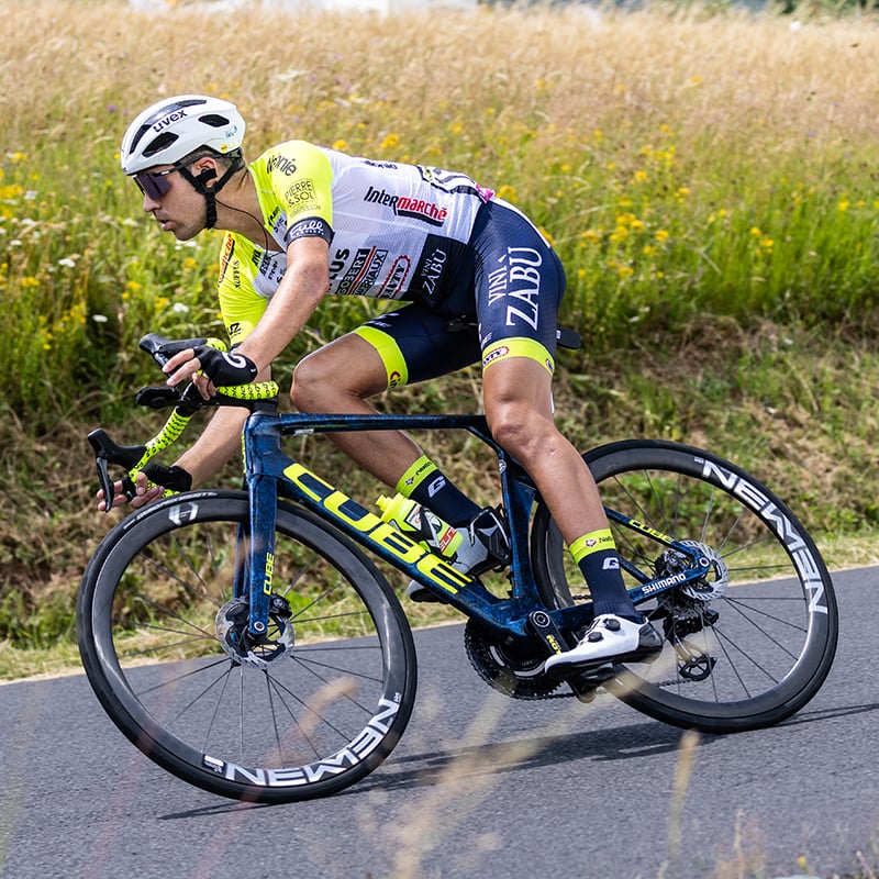 Radfahrer auf Cube Litening Rennrad, trägt Rennanzug und Helm, fährt auf einer Landstraße.