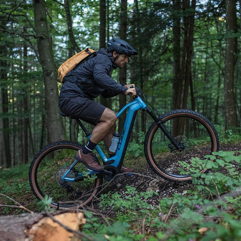 Mann fährt ein blaues Cube E-Mountainbike im Wald. Ideal für Offroad-Fahrten und sportliche Abenteuer.