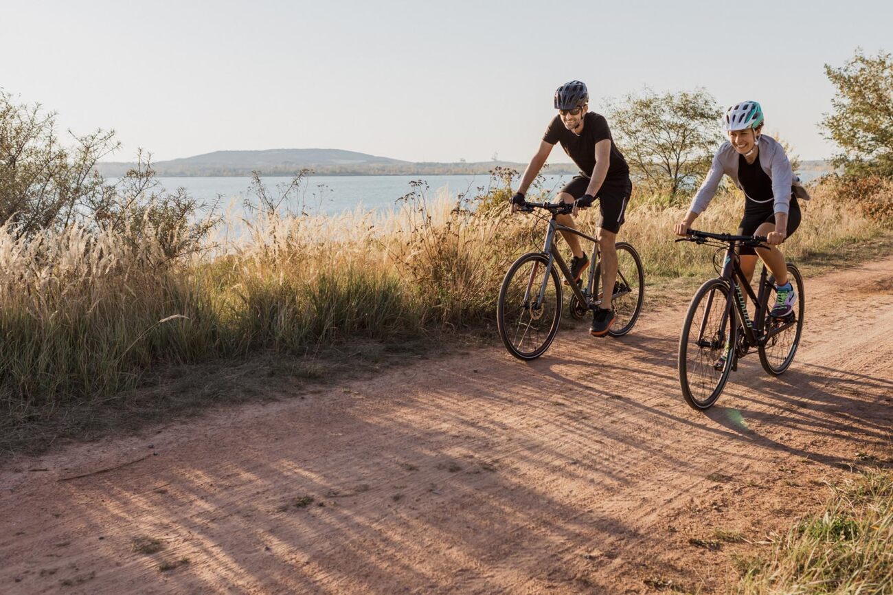 Zwei Radfahrer auf einer Schotterstraße mit Specialized-City-Urban-Bikes in ländlicher Landschaft bei Sonnenuntergang.