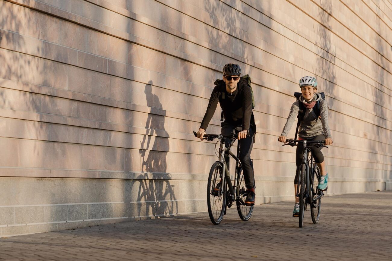 Zwei Personen fahren mit Specialized City- und Urban-Fahrrädern an einer Mauer entlang, geeignet für Stadtfahrten.