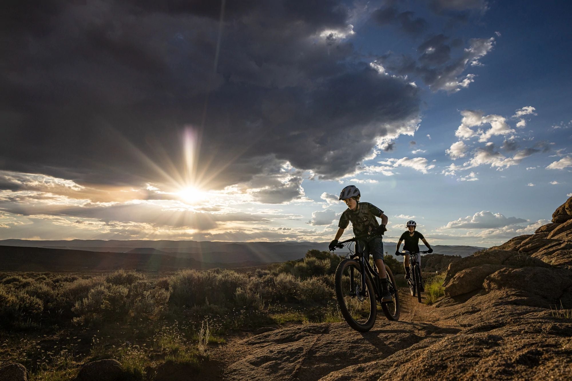 Zwei Personen fahren Trek-Mountainbikes im Gelände bei Sonnenuntergang. Ideal für Abenteuer- und Outdoor-Enthusiasten.
