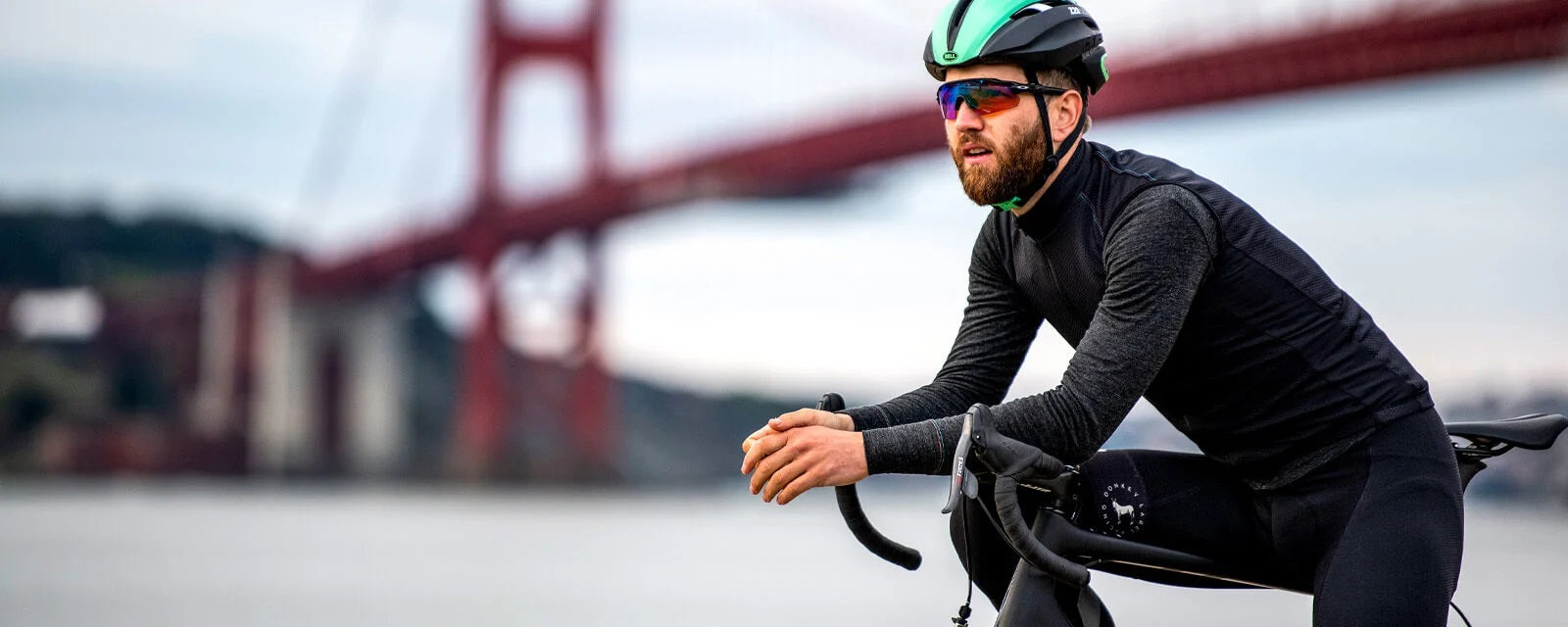 Mann auf Rennrad mit Bell-Helm und Sonnenbrille vor Golden Gate Bridge.
