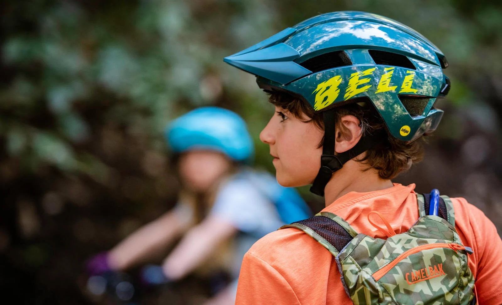 Kind mit Bell-Fahrradhelm und CamelBak-Rucksack im Wald, zielgerichtet für Outdoor-Abenteuer und Radsport.