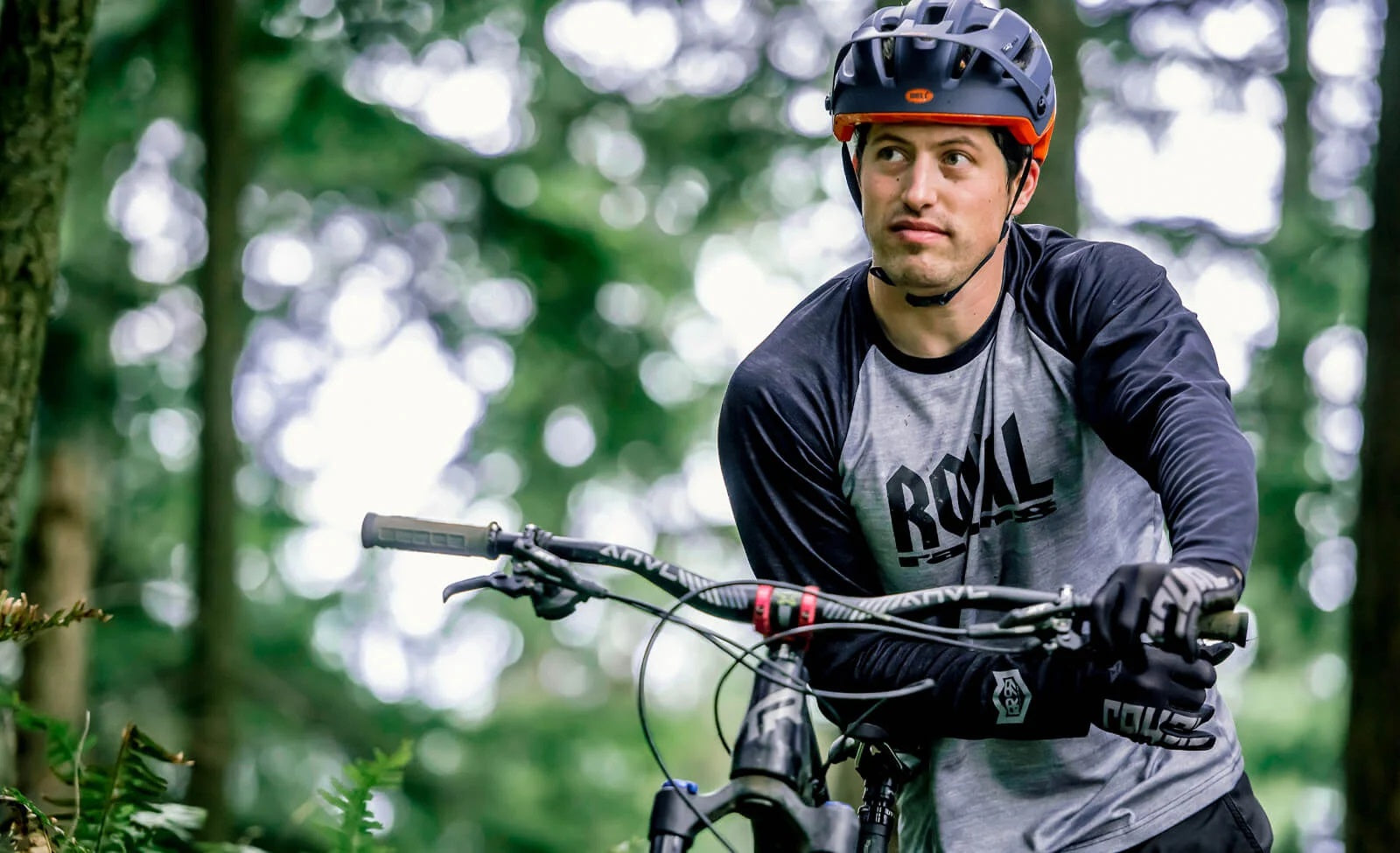 Mann mit Helm und Mountainbike im Wald, Helm mit Bell-Logo, geeignet für Offroad-Fahrer.