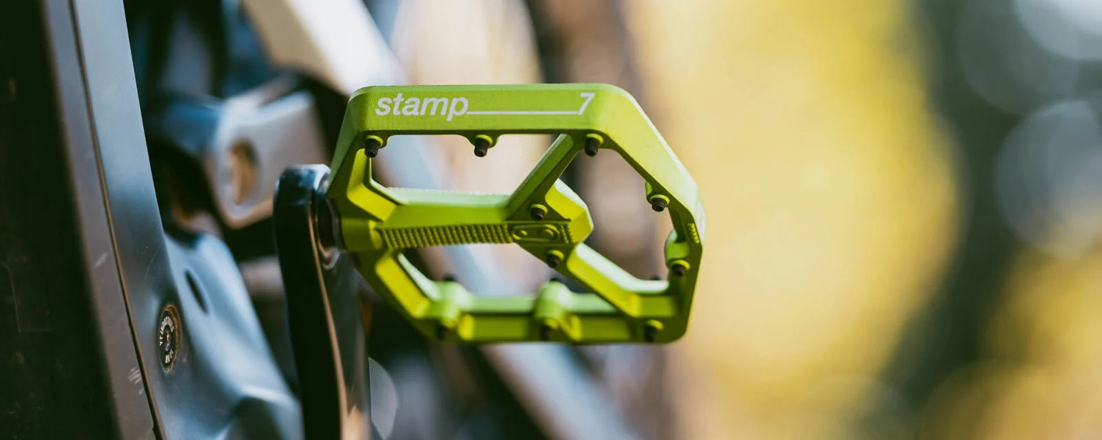 Grünes Stamp 7 Fahrradpedal von Crankbrothers, montiert an einem Fahrrad, ideal für Mountainbiker.