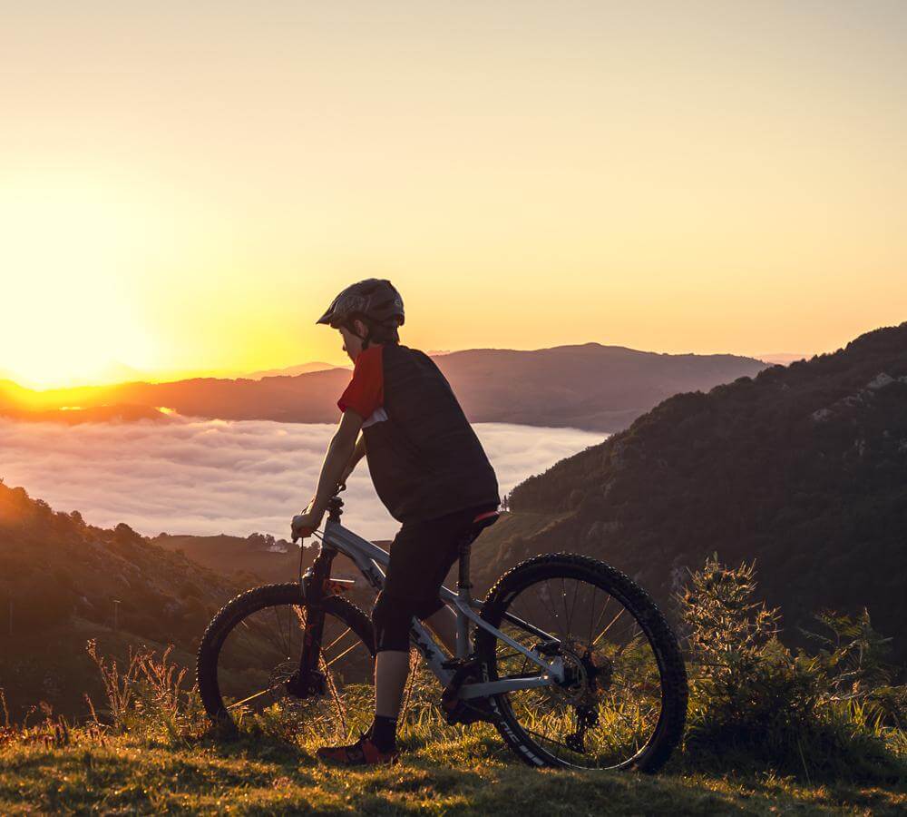 Kind auf Orbea Laufey Junior Mountainbike bei Sonnenuntergang in den Bergen. Ideal für junge Outdoor-Enthusiasten.
