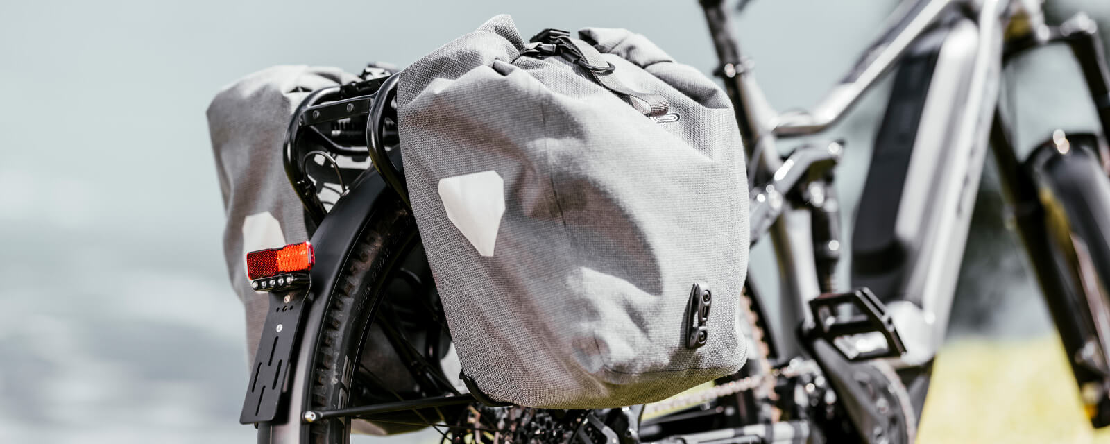 Fahrrad mit grauen Satteltaschen am Gepäckträger, rote Rückleuchte; ideal für Pendler und Tourenfahrer.