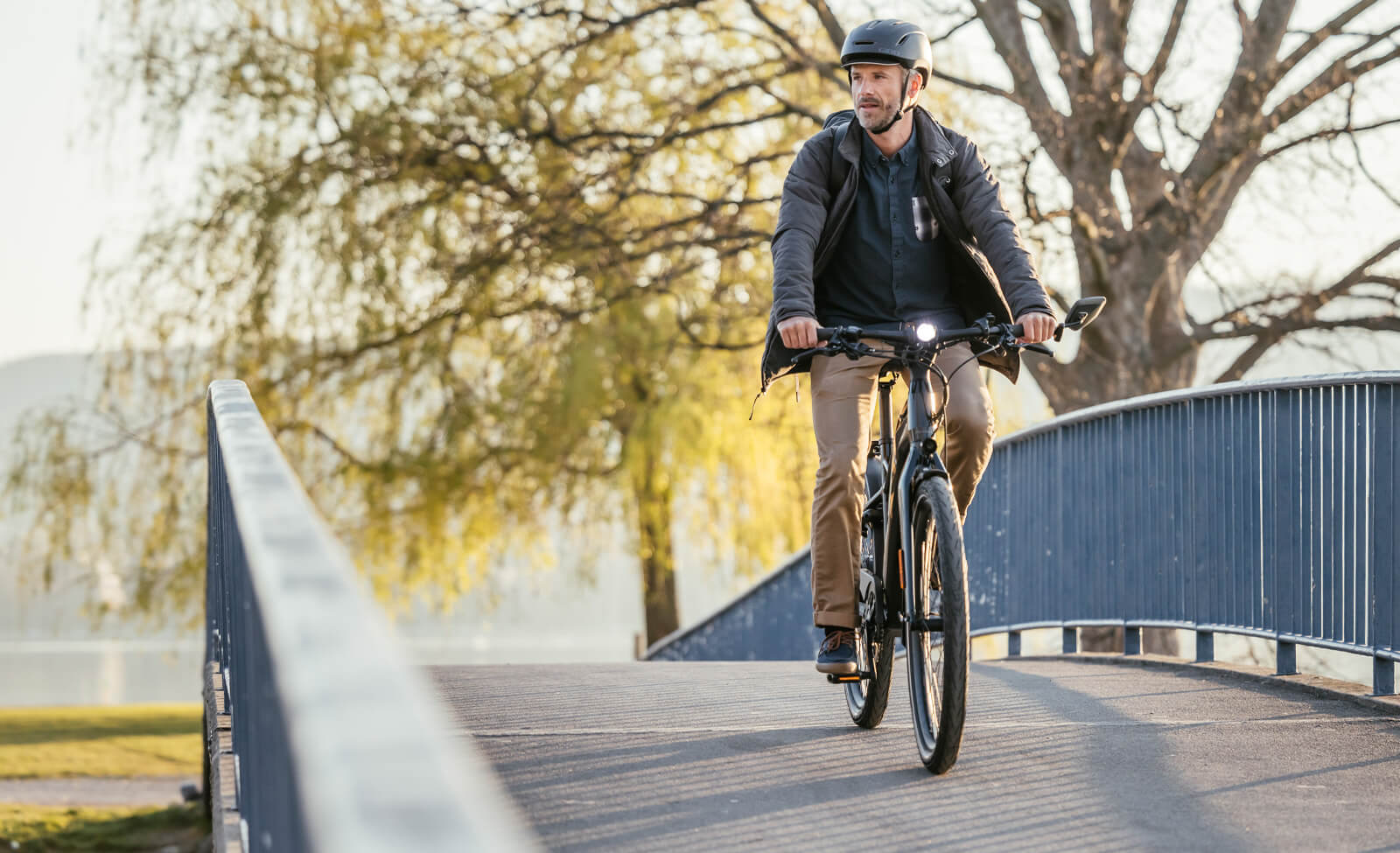 Mann fährt bei Tageslicht ein E-Bike der Marke Flyer über eine Brücke, mit Helm und Freizeitkleidung.